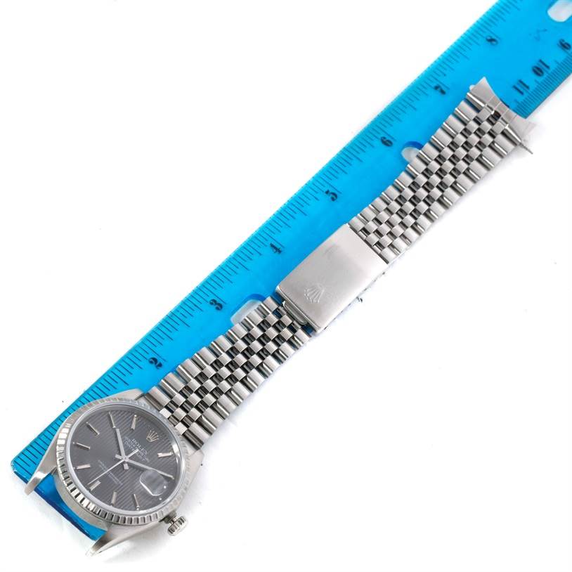 The Rolex Datejust 16220 Men
s Stainless Steel Grey Dial 16220 Men
s Stainless Steel Grey Dial watch is shown from a top-down angle, including its face, bracelet, and deployment clasp, alongside a ruler.