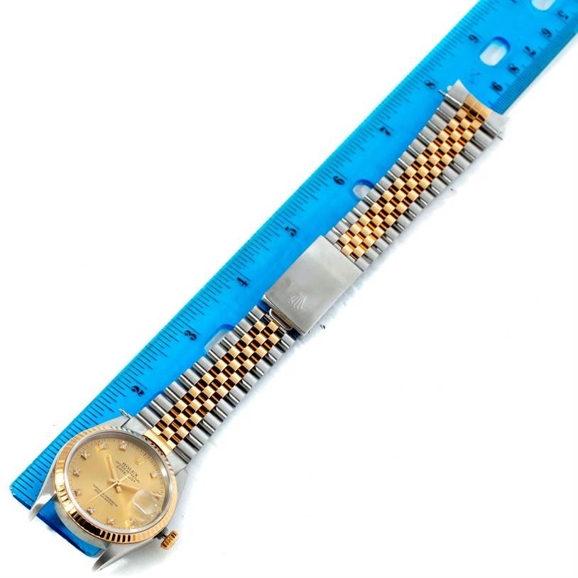 The Rolex Datejust 16233 Men's Steel and Gold (two tone) Champagne Dial 16233 Men's Steel and Gold (two tone) Champagne Dial watch, shown top-down, includes the face, strap, and clasp, alongside a blue ruler for scale.