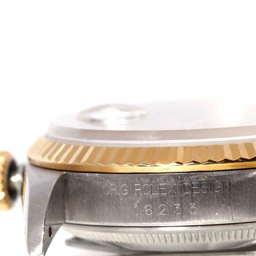 The image shows a close-up side view of a Rolex Datejust 16233 Men's Steel and Gold (two tone) Champagne Dial 16233 Men's Steel and Gold (two tone) Champagne Dial watch, specifically focusing on the engraved case and the crown.