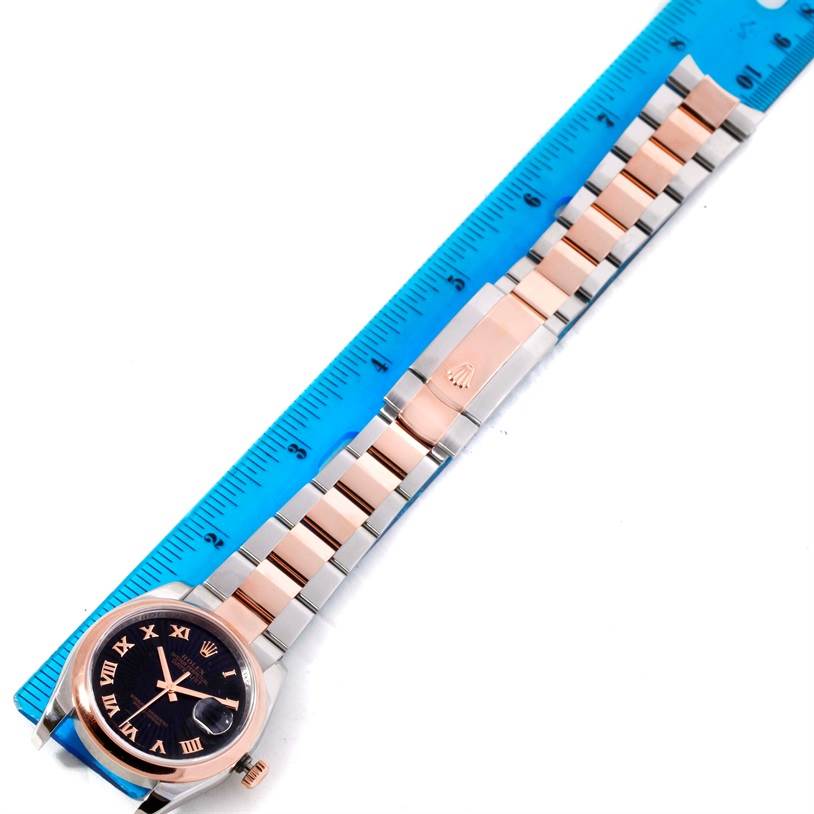 The image shows the front view of a Rolex Datejust 116201 Men
s Steel and Gold (two tone) Black Dial 116201 Men
s Steel and Gold (two tone) Black Dial watch, highlighting its face, bezel, and band next to a blue ruler.