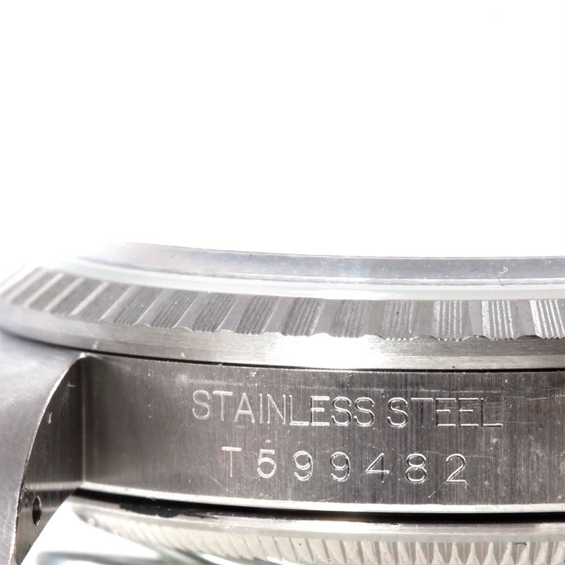 The image shows a close-up side view of a Rolex Datejust 16220 Men
s Stainless Steel Black Dial 16220 Men
s Stainless Steel Black Dial watch, highlighting its stainless steel case and engraving.