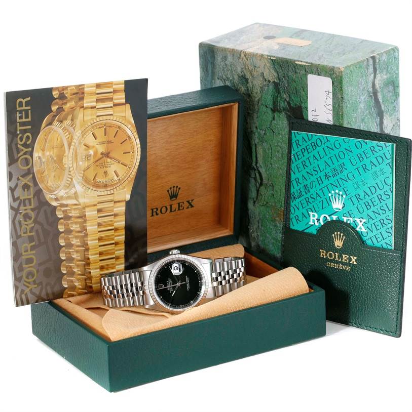 The image shows a Rolex Datejust 16220 Men
s Stainless Steel Black Dial 16220 Men
s Stainless Steel Black Dial watch, its box, booklets, and accessories, displayed at a front angle.