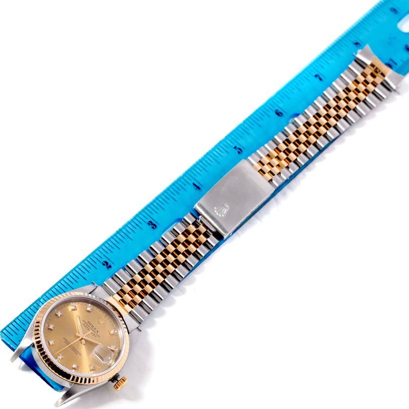 This image shows a Datejust watch by Rolex placed alongside a blue ruler, highlighting the face and bracelet.