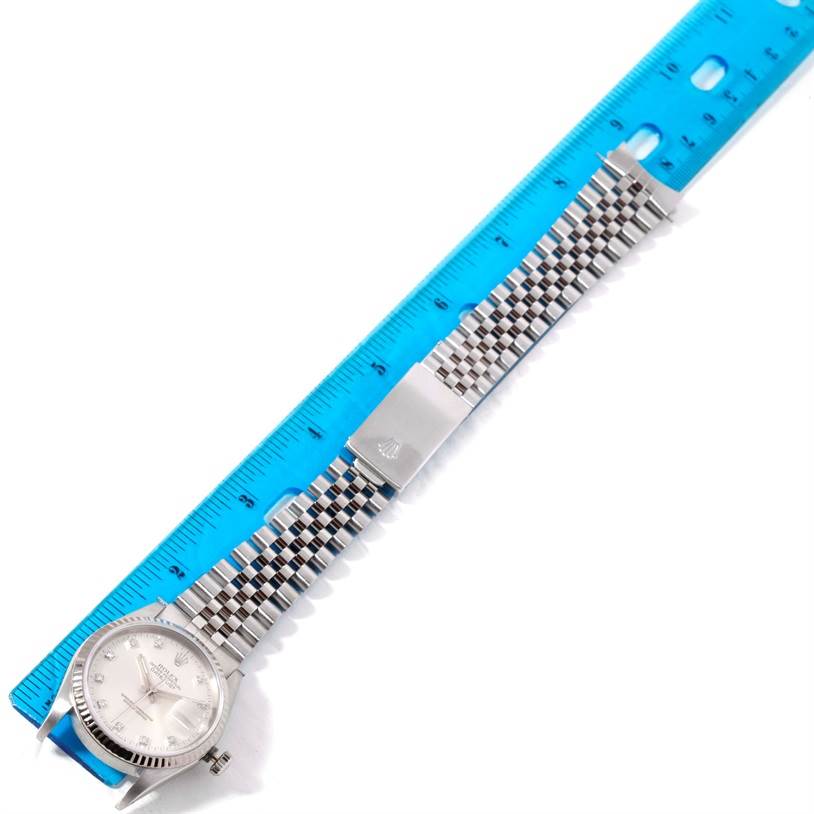 The image shows a full view of a Rolex Datejust 16234 Men's Stainless Steel Silver Dial 16234 Men's Stainless Steel Silver Dial model laid next to a blue ruler.