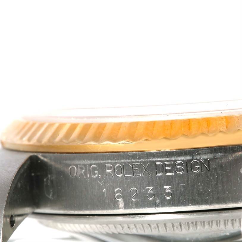 The image shows a close-up, side angle of a Rolex Datejust 16233 Men's Steel and Gold (two tone) Silver Dial 16233 Men's Steel and Gold (two tone) Silver Dial watch, highlighting its bezel and engraved case with model number 16233.