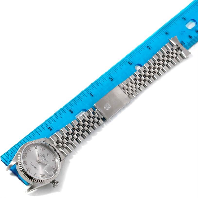 This image shows a top-down view of a Rolex Datejust 16234 Men's Stainless Steel Silver Dial 16234 Men's Stainless Steel Silver Dial watch, focusing on the face and the bracelet placed next to a blue ruler.