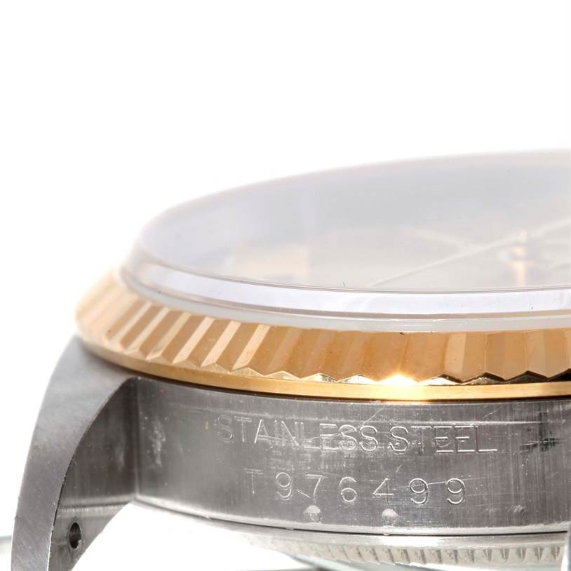 This image shows a side angle of the Rolex Datejust 16233 Men's Steel and Gold (two tone) Champagne Dial 16233 Men's Steel and Gold (two tone) Champagne Dial watch, highlighting its stainless steel case, fluted bezel, and part of the serial number.