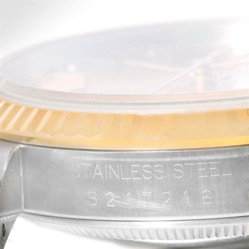 The image shows a side angle of a Rolex Datejust 16233 Men's Steel and Gold (two tone) Champagne Dial 16233 Men's Steel and Gold (two tone) Champagne Dial watch, specifically the case with "STAINLESS STEEL" engraving visible.