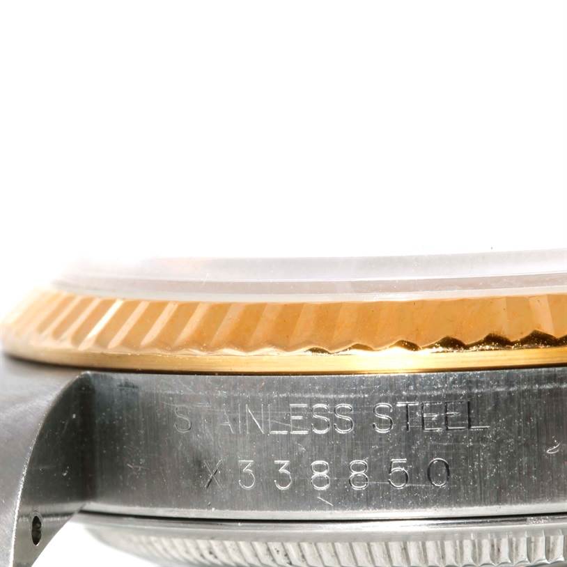 The image displays a close-up side view of the Rolex Datejust 16233 Men's Steel and Gold (two tone) Silver Dial 16233 Men's Steel and Gold (two tone) Silver Dial watch, focusing on the stainless steel and gold fluted bezel, including part of the watch case and serial number.