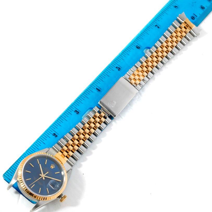 The Rolex Datejust 16233 Men's Steel and Gold (two tone) Blue Dial 16233 Men's Steel and Gold (two tone) Blue Dial watch is shown laid flat with its dial, bezel, and bracelet displayed alongside a blue ruler for scale.