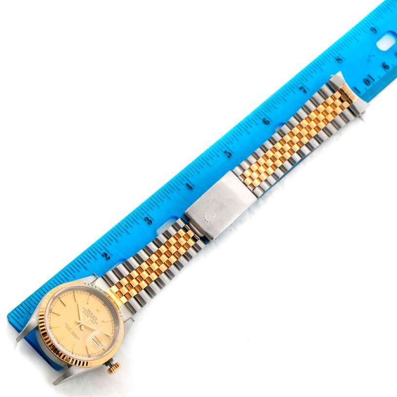 The image shows the Rolex Datejust 16233 Men's Steel and Gold (two tone) Champagne Dial 16233 Men's Steel and Gold (two tone) Champagne Dial watch laid flat next to a ruler, displaying its face and jubilee bracelet.