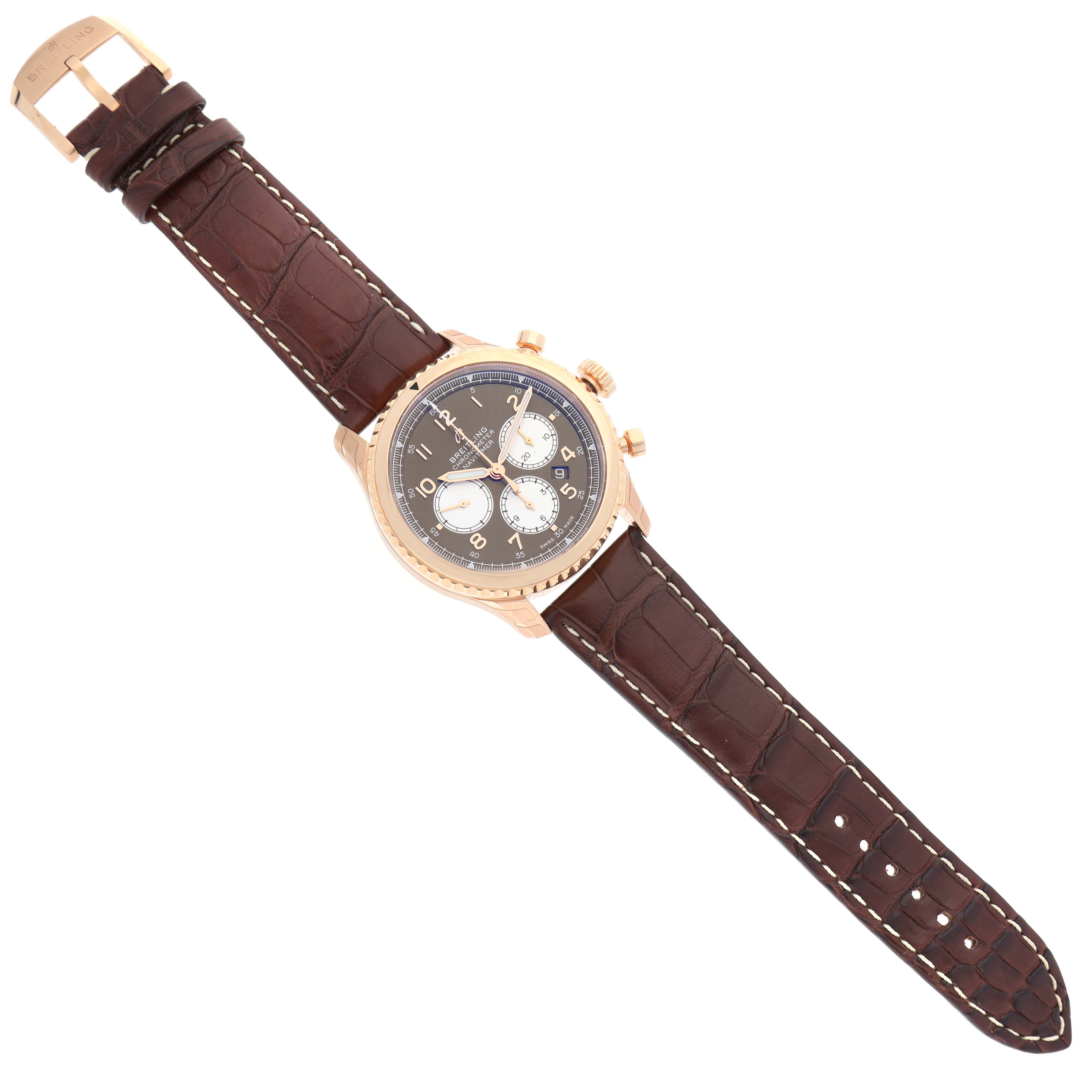 This image shows a top-down view of a Breitling Navitimer watch with a brown leather strap and gold-tone case.
