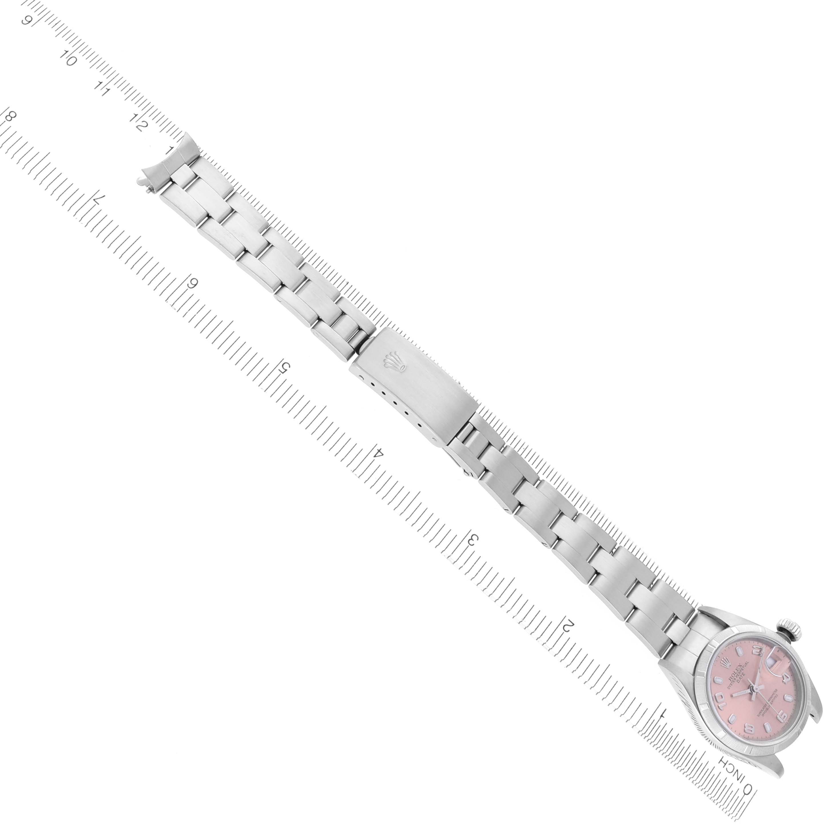 The Rolex Date 79190 Women's Stainless Steel Pink Dial 79190 Women's Stainless Steel Pink Dial watch is shown from a top-down angle, displaying the bracelet and clasp on a ruler for scale.