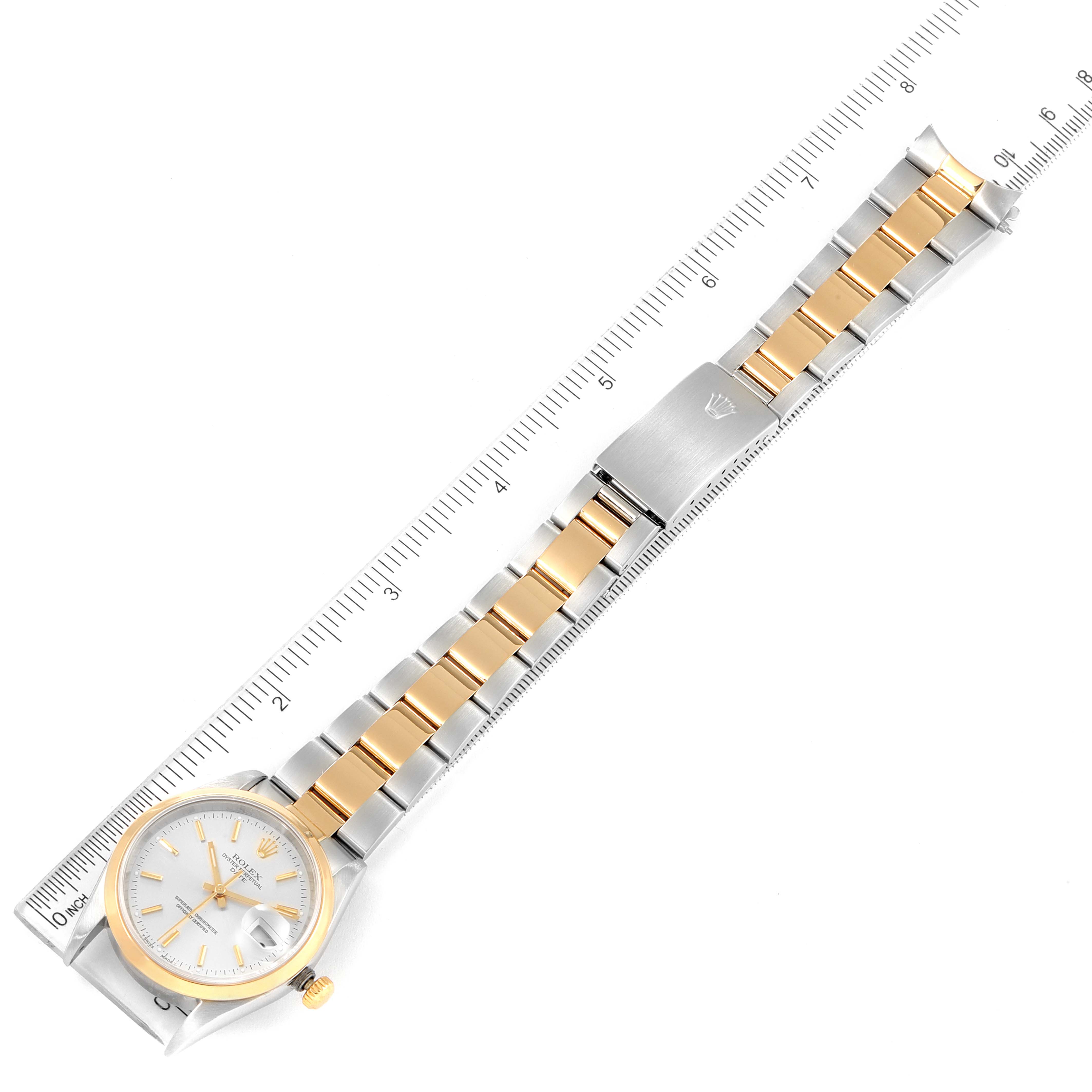 The image shows a top-down view of a Rolex Date 15203 Men's Steel and Gold (two tone) Silver Dial 15203 Men's Steel and Gold (two tone) Silver Dial model watch with a two-tone bracelet placed against a measuring ruler.
