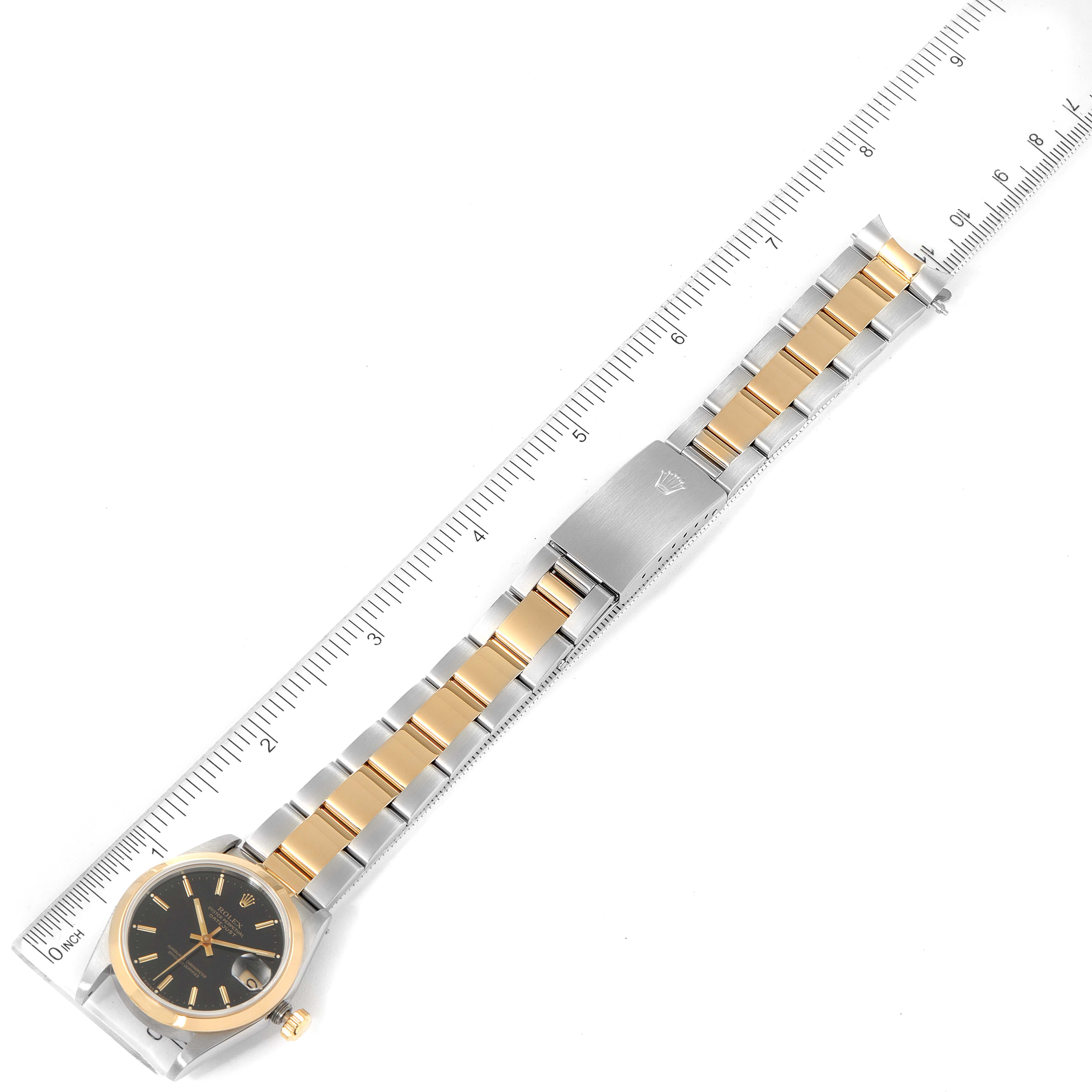 The image shows a Mid-Size Rolex watch laid flat with a metal and gold band, next to a ruler for size reference.