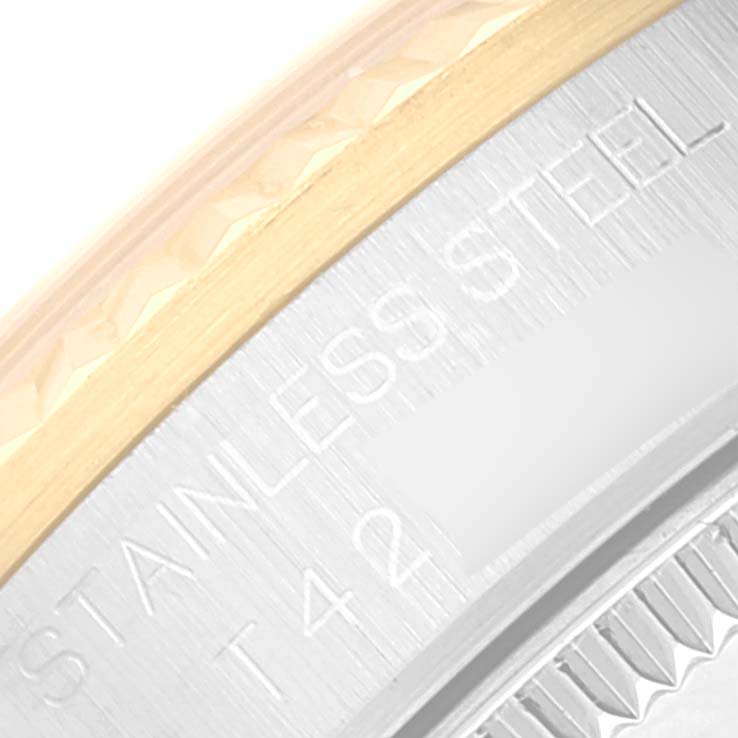 This close-up angle shows the details on the bezel and case back of the mid-size Rolex watch, indicating "STAINLESS STEEL" and part of serial information.