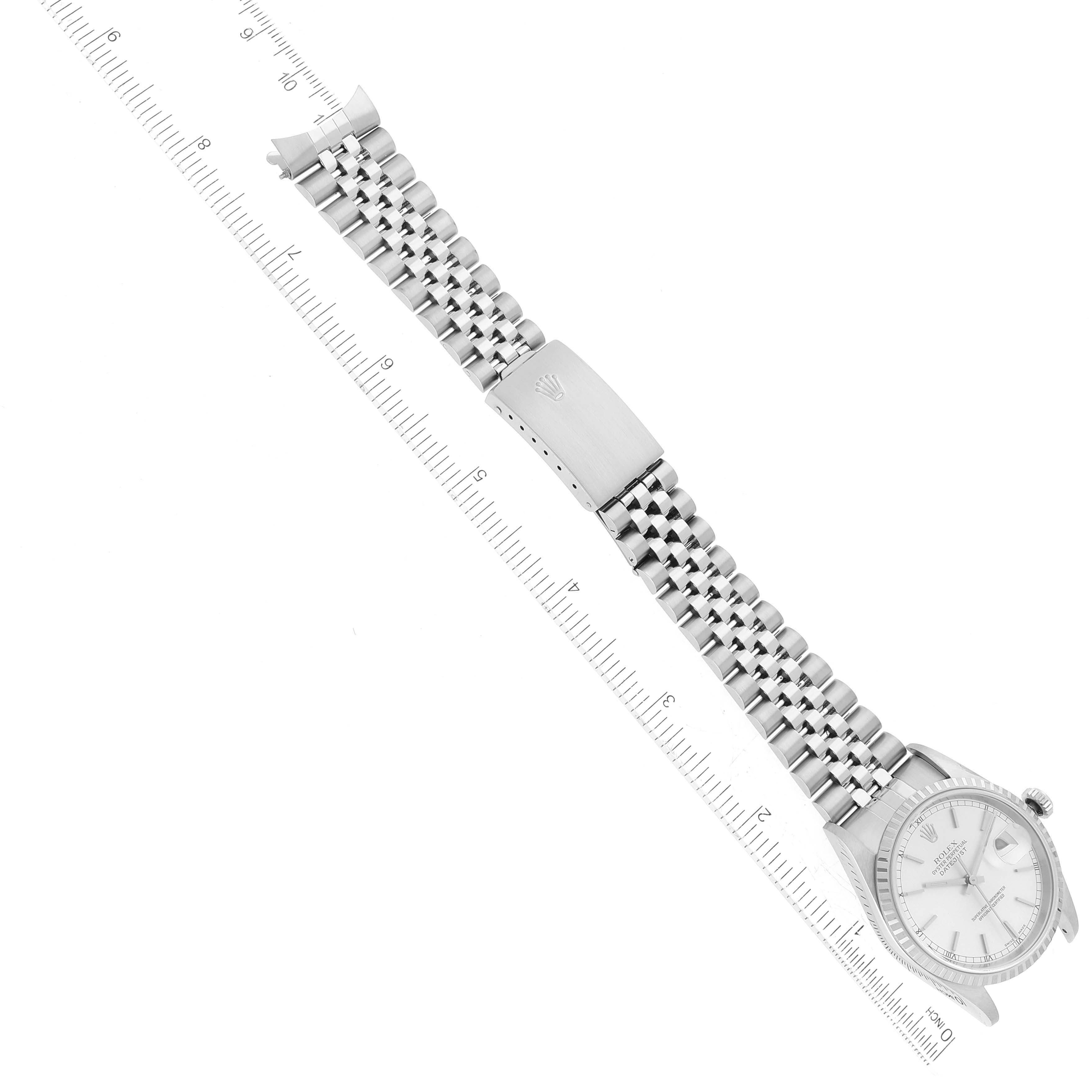 The Rolex Datejust 16220 Men's Stainless Steel Silver Dial 16220 Men's Stainless Steel Silver Dial watch is shown at an aerial angle, displaying the face, bracelet, and clasp above a ruler.