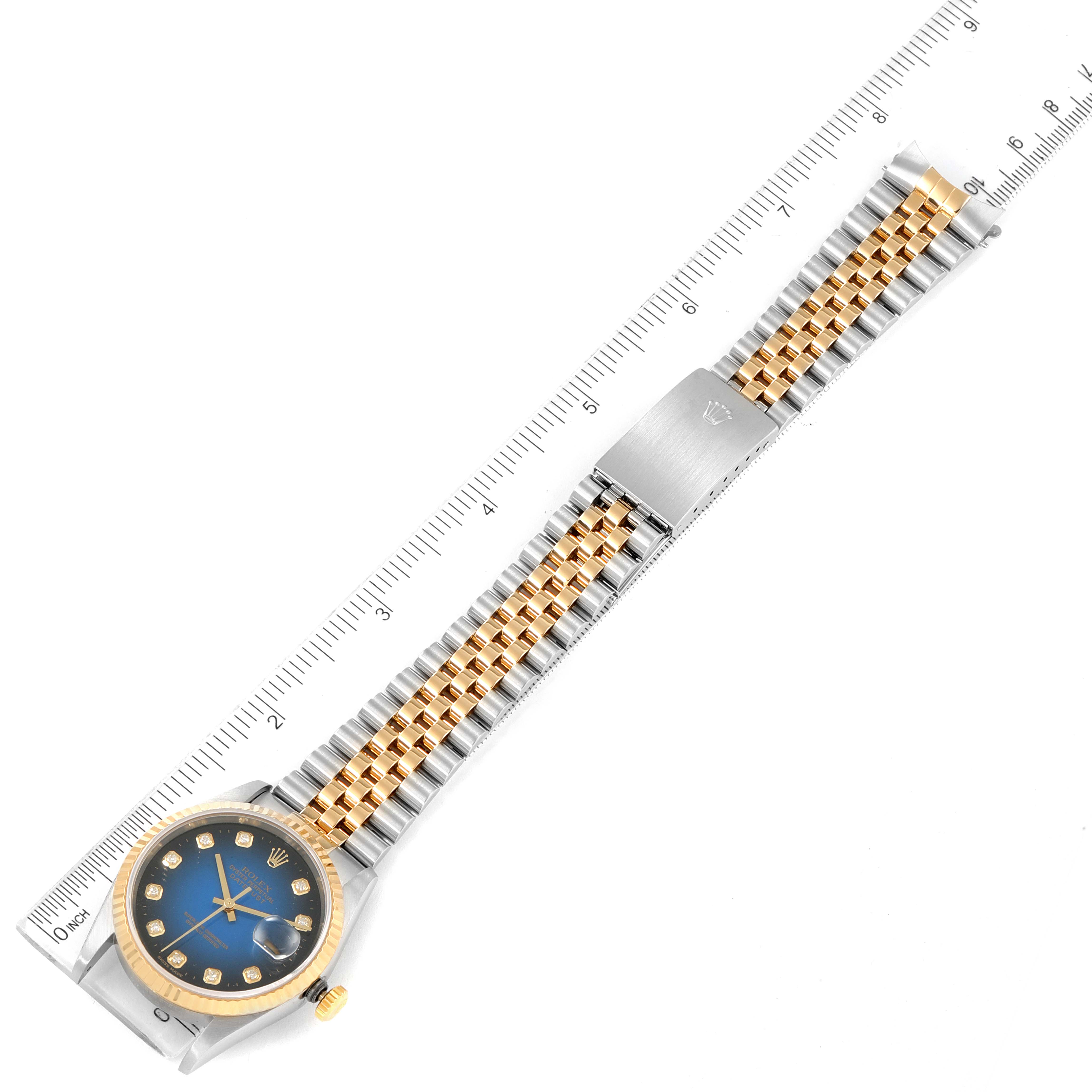The image shows a top view of a Rolex Datejust 16233 Men's Steel and Gold (two tone) Blue Dial 16233 Men's Steel and Gold (two tone) Blue Dial watch, including the dial, bezel, crown, bracelet, and clasp with a measuring ruler beside it.