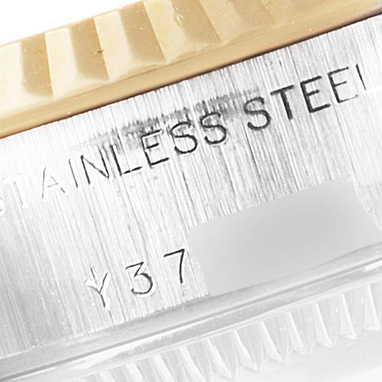 This close-up image shows the edge of the bezel and part of the case of a Rolex Datejust 79173 Women
s Steel and Gold (two tone) Champagne Dial 79173 Women
s Steel and Gold (two tone) Champagne Dial watch, featuring "STAINLESS STEEL" engraving.