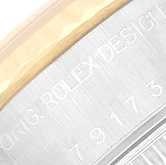 The image shows a close-up of the side of a Rolex Datejust 79173 Women's Steel and Gold (two tone) Champagne Dial 79173 Women's Steel and Gold (two tone) Champagne Dial watch, highlighting the engraved model number and part of the bezel.