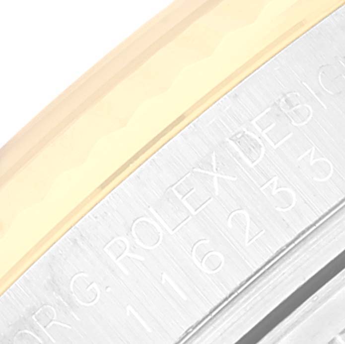 The image shows a close-up of the Rolex Datejust 116233 Men's Steel and Gold (two tone) Champagne Dial 116233 Men's Steel and Gold (two tone) Champagne Dial watch case engraving and part of the bezel.