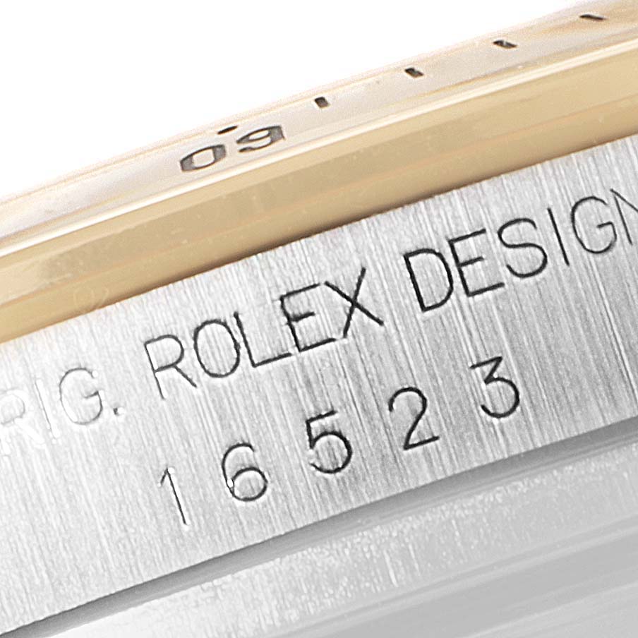 A close-up image of the case side of a Rolex Daytona 16523 Men
s Steel and Gold (two tone) Black Dial 16523 Men
s Steel and Gold (two tone) Black Dial watch, showing the model number "16523" and "Rolex Design" engraving.