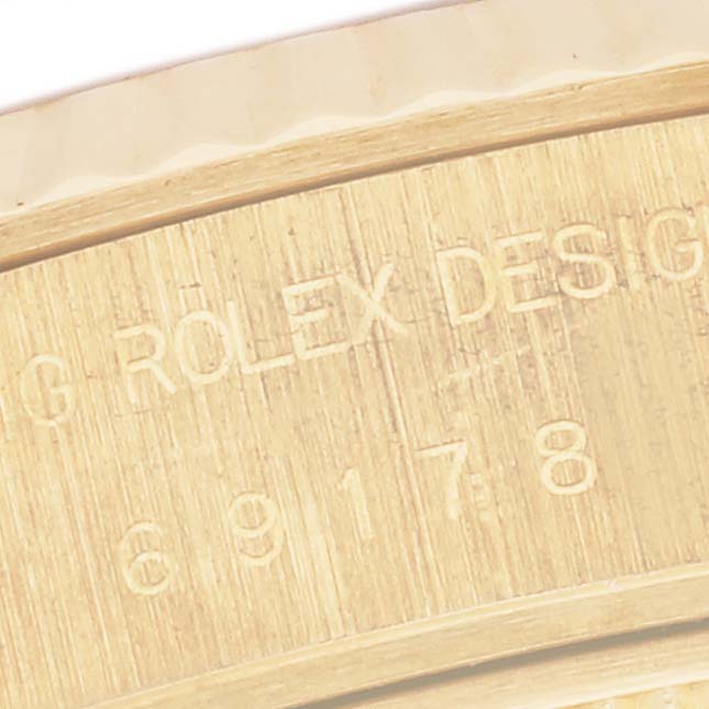 The image shows a close-up of the engraved edge of a Rolex President 69178 Women's Yellow Gold Champagne Dial 69178 Women's Yellow Gold Champagne Dial model watch case.