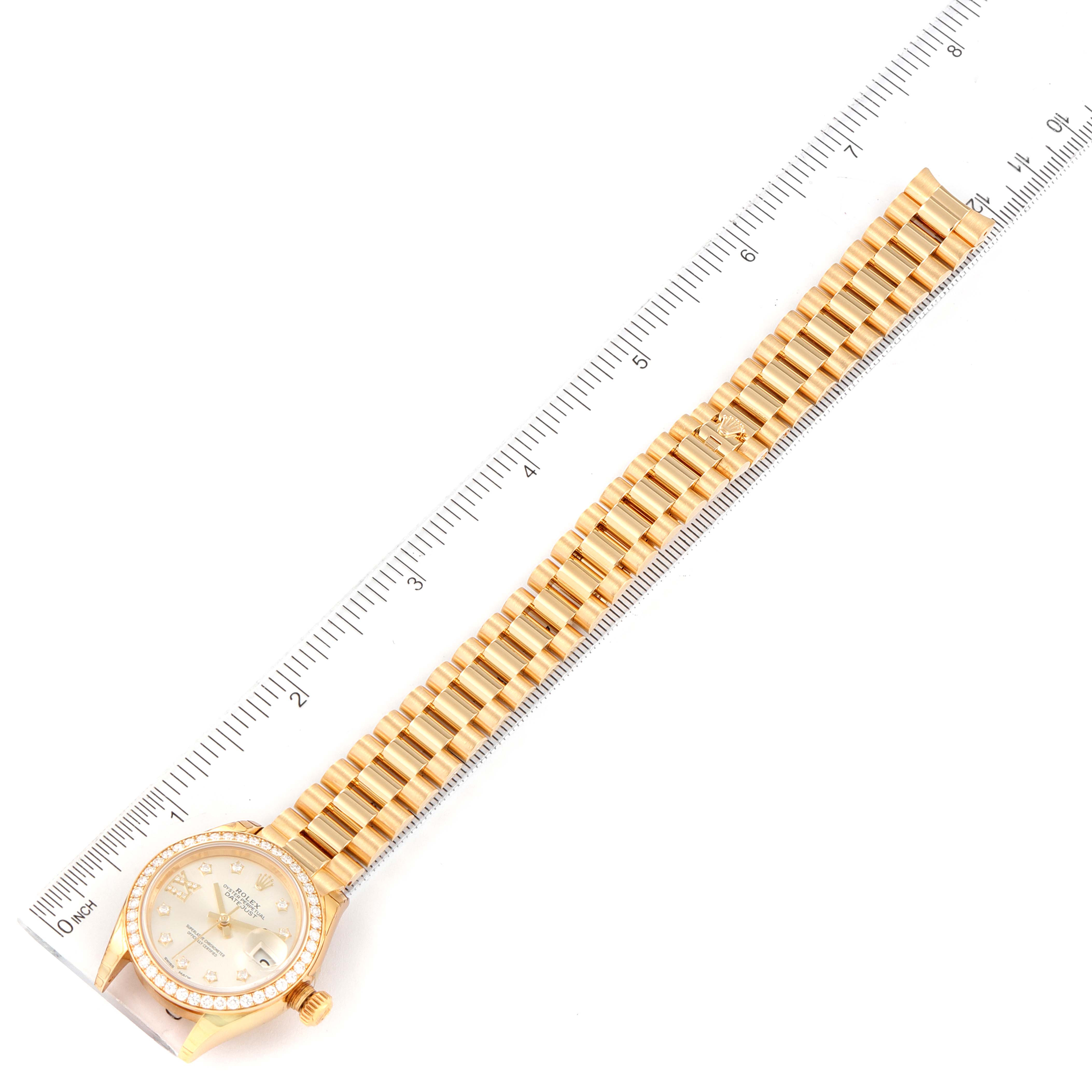 The Rolex President 279138 Women's Yellow Gold Silver Dial 279138 Women's Yellow Gold Silver Dial model watch is shown fully extended with a view of the face, bracelet, and a measuring ruler beside it.