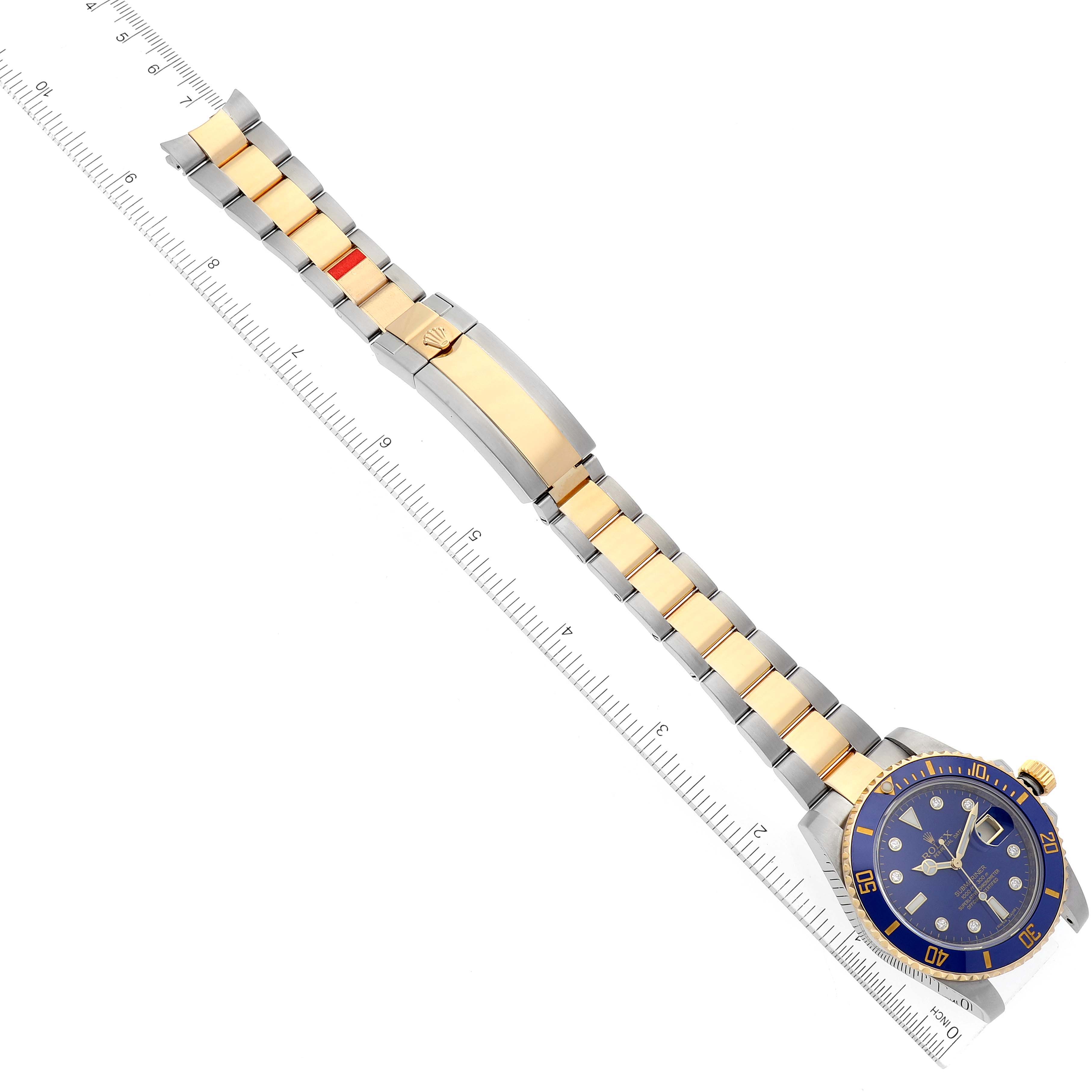 The image shows a top-down view of a Rolex Submariner 116613 Men's Steel and Gold (two tone) Blue Dial 116613 Men's Steel and Gold (two tone) Blue Dial watch with its bracelet and ruler for scale.