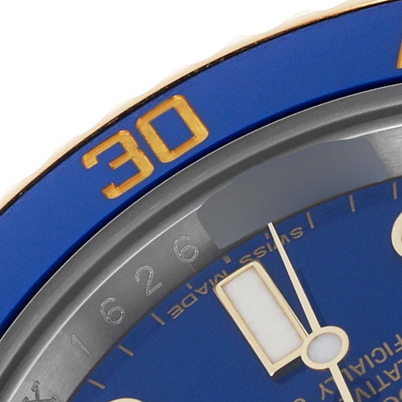 A close-up of a Rolex Submariner 116613 Men's Steel and Gold (two tone) Blue Dial 116613 Men's Steel and Gold (two tone) Blue Dial watch showing part of the blue bezel and markings along with the minute hand.