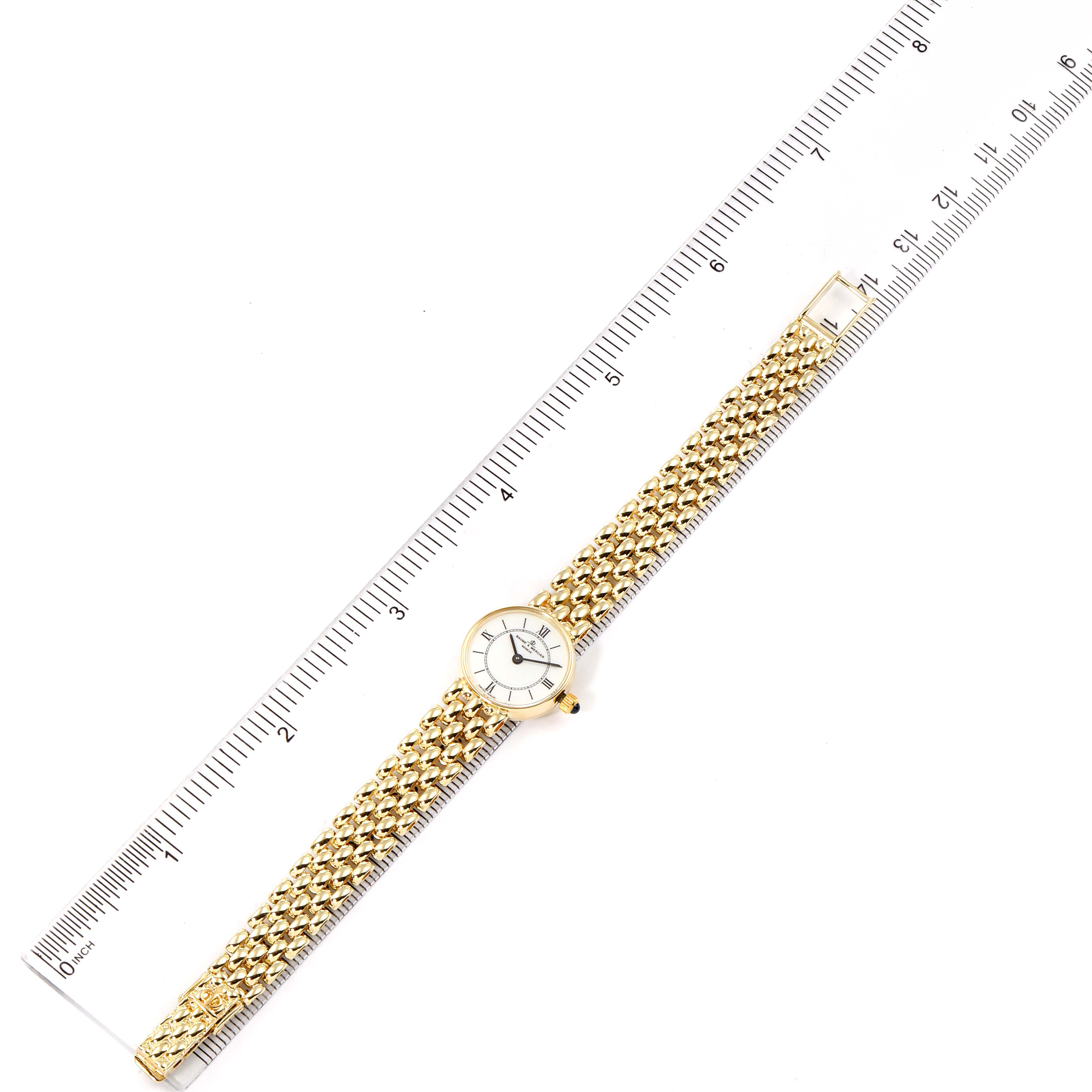 The image shows the Baume & Mercier  Women's Yellow Gold White Dial  Women's Yellow Gold White Dial 14k Yellow Gold White Dial Cocktail Ladies Watch laid flat beside a ruler for scale.