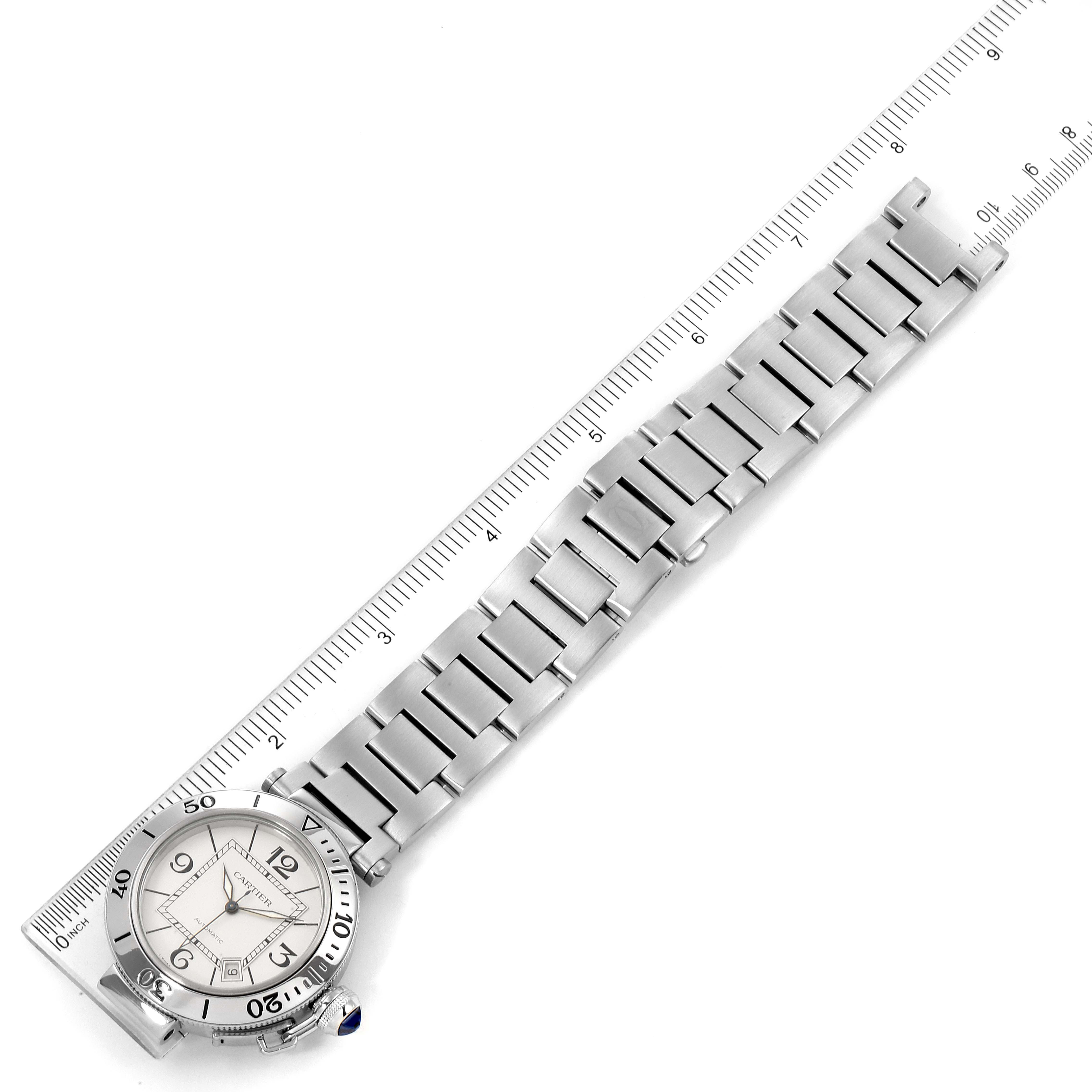This image shows a Cartier Pasha W31080M7 Men
s Stainless Steel Silver Dial W31080M7 Men
s Stainless Steel Silver Dial watch placed next to a ruler, displaying the watch face and the entire metal bracelet.