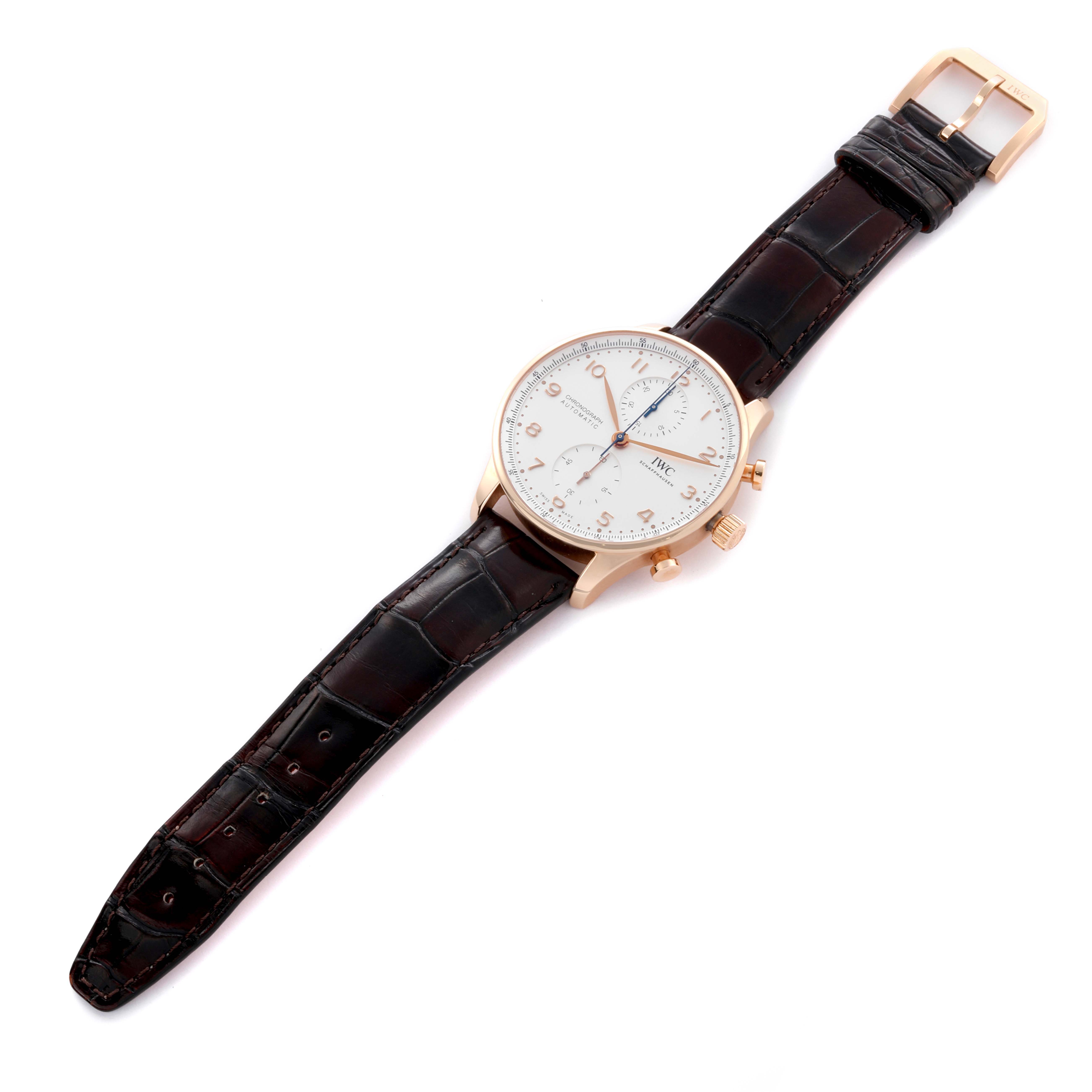 The IWC Portuguese IW371611 Men's Rose Gold Silver Dial IW371611 Men's Rose Gold Silver Dial watch is shown from a top-down angle, displaying the full face, leather strap, case, crown, and pushers.