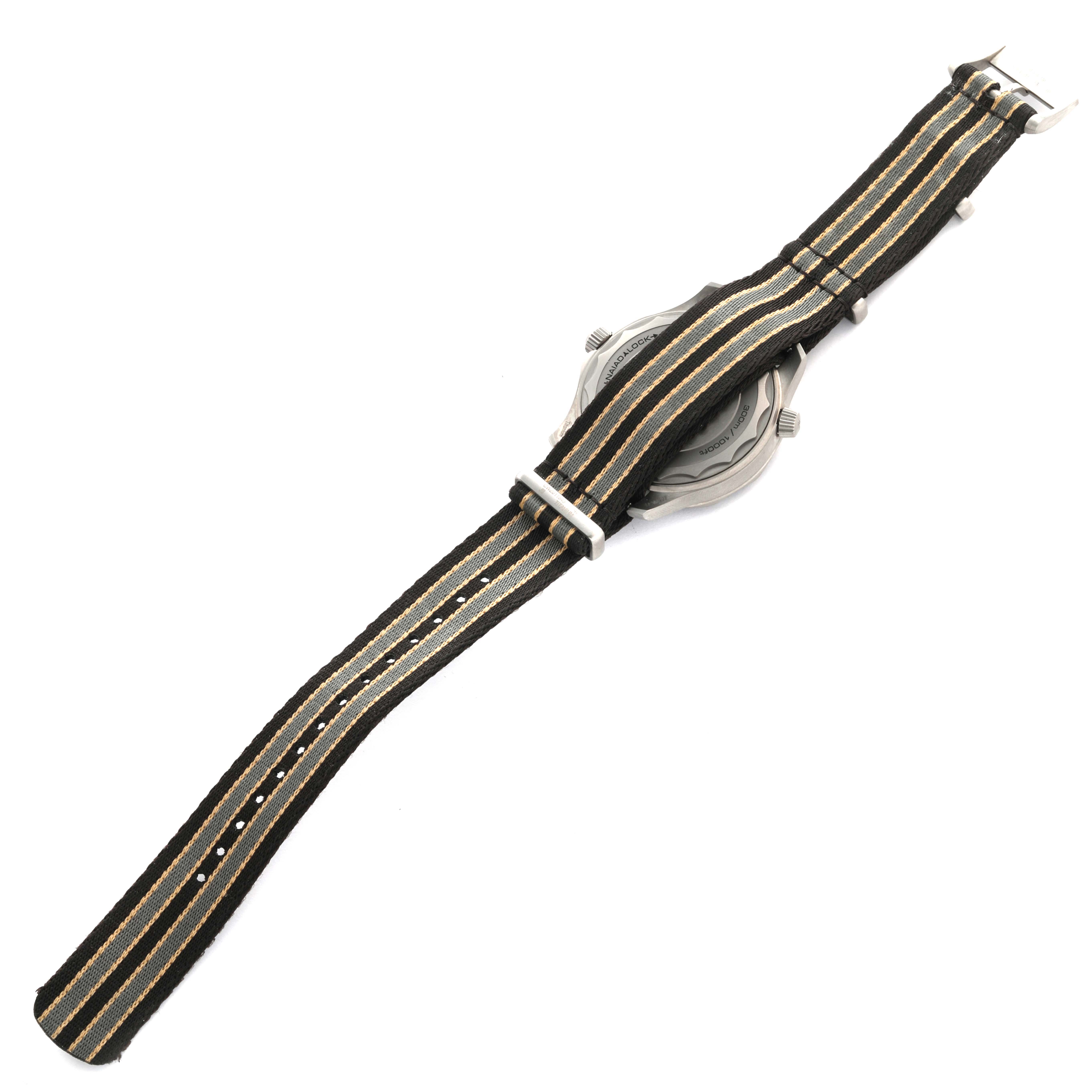 The Omega Seamaster 210.92.42.20.01.001 Men's Titanium Brown Dial 210.92.42.20.01.001 Men's Titanium Brown Dial watch is shown from the back, highlighting its striped NATO strap and case back with visible crown and buttons.