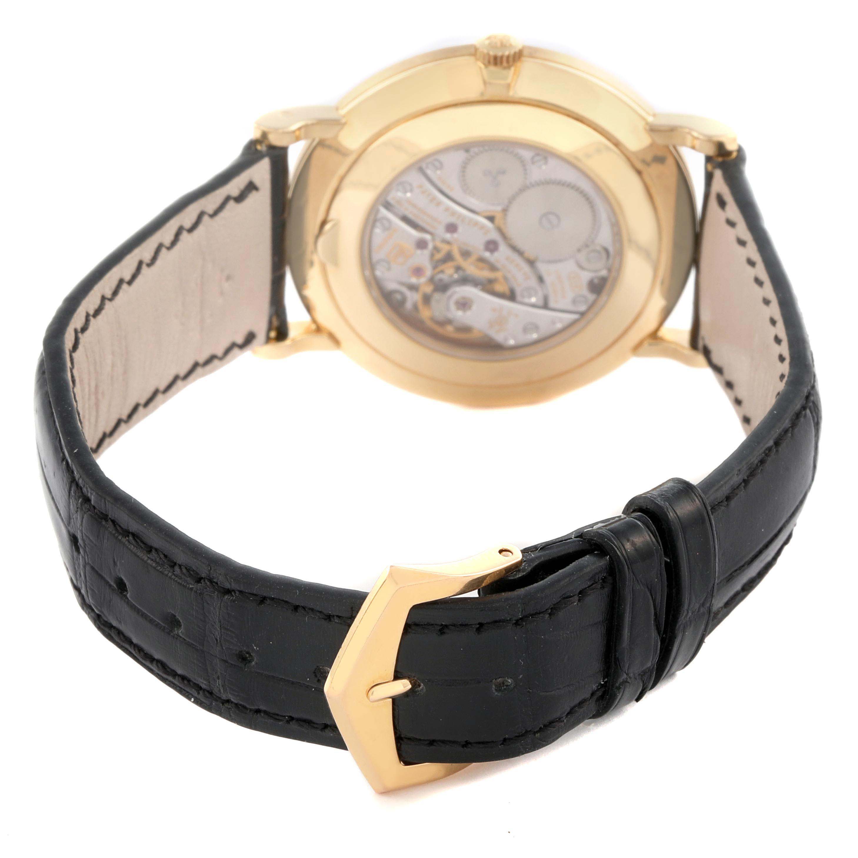 The image shows the back of a Patek Philippe Calatrava 5119J Men's Yellow Gold White Dial 5119J Men's Yellow Gold White Dial watch, highlighting the movement and black leather strap.