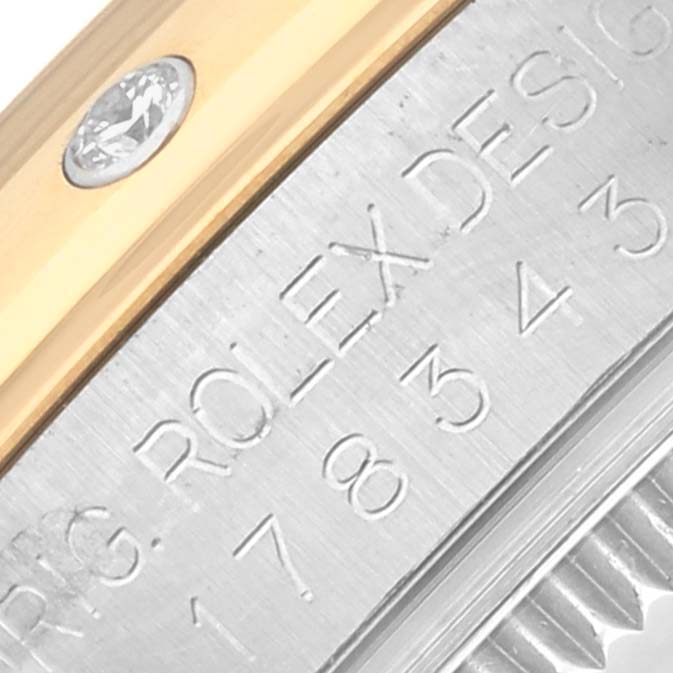 The close-up image shows a side view of a Rolex Mid-Size 178343 Women's Steel and Gold (two tone) Silver Dial 178343 Women's Steel and Gold (two tone) Silver Dial model, focusing on the engraved text and part of the bezel with a diamond.