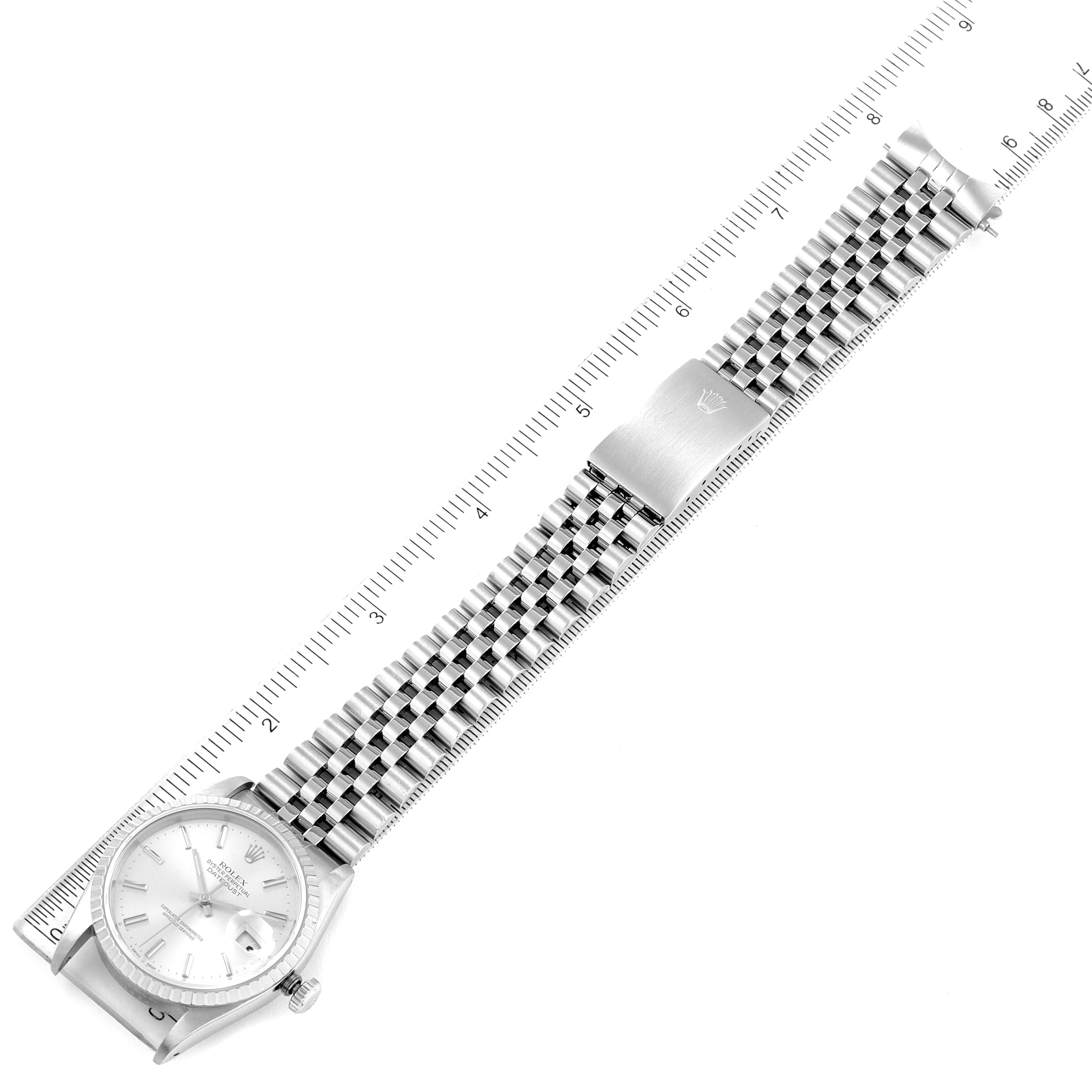 The image shows a top-down view of a Rolex Datejust 16220 Men's Stainless Steel Silver Dial 16220 Men's Stainless Steel Silver Dial watch, highlighting the face, bracelet, and clasp with a ruler for scale.