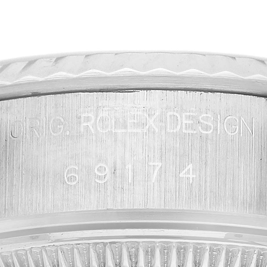 The image shows a close-up of the engraved side of the Rolex Datejust 69174 Women's Stainless Steel Silver Dial watch, displaying the model number and design details.