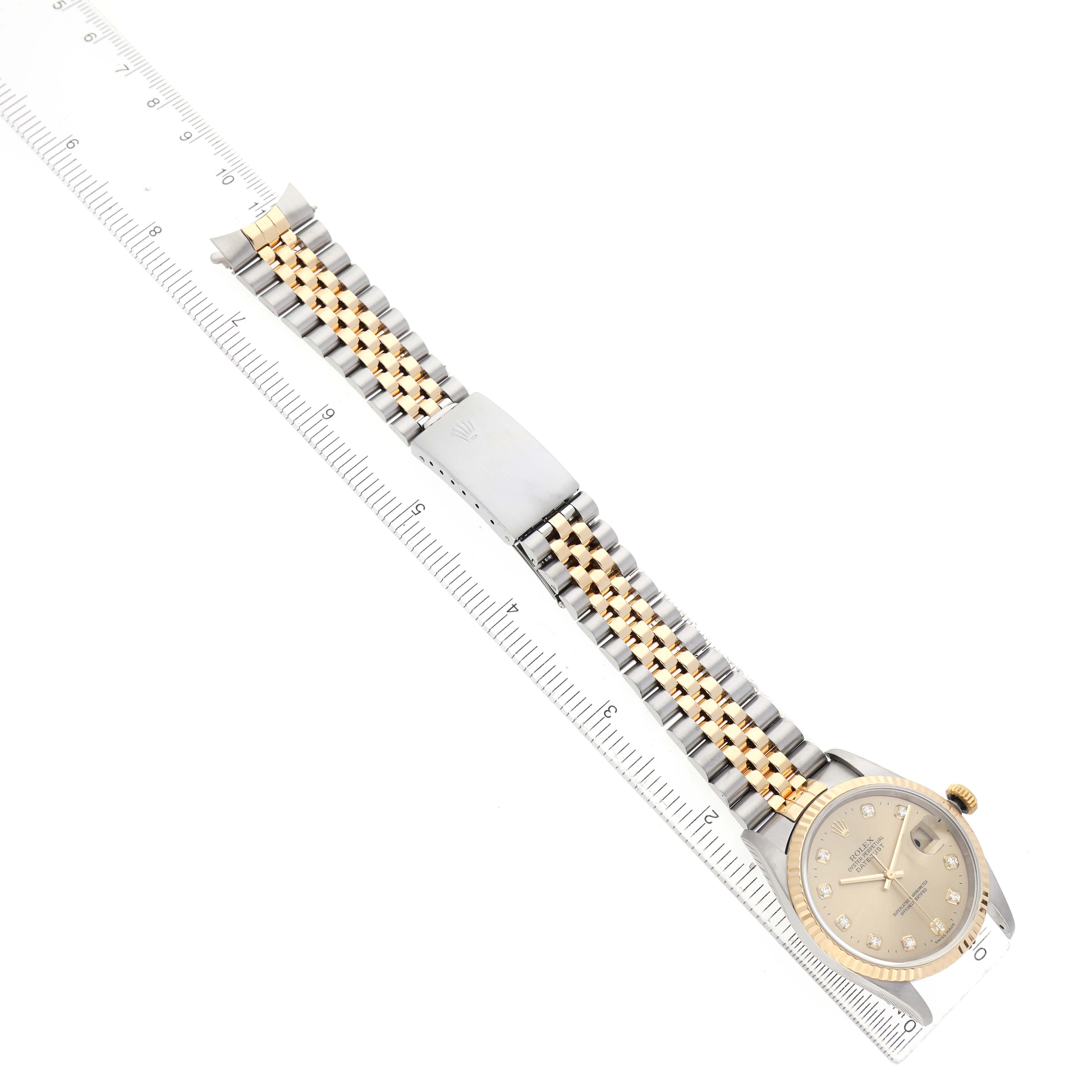 The Rolex Datejust 16233 Men's Steel and Gold (two tone) Champagne Dial is shown from a top-down angle, highlighting its dial and jubilee bracelet alongside a ruler for scale.