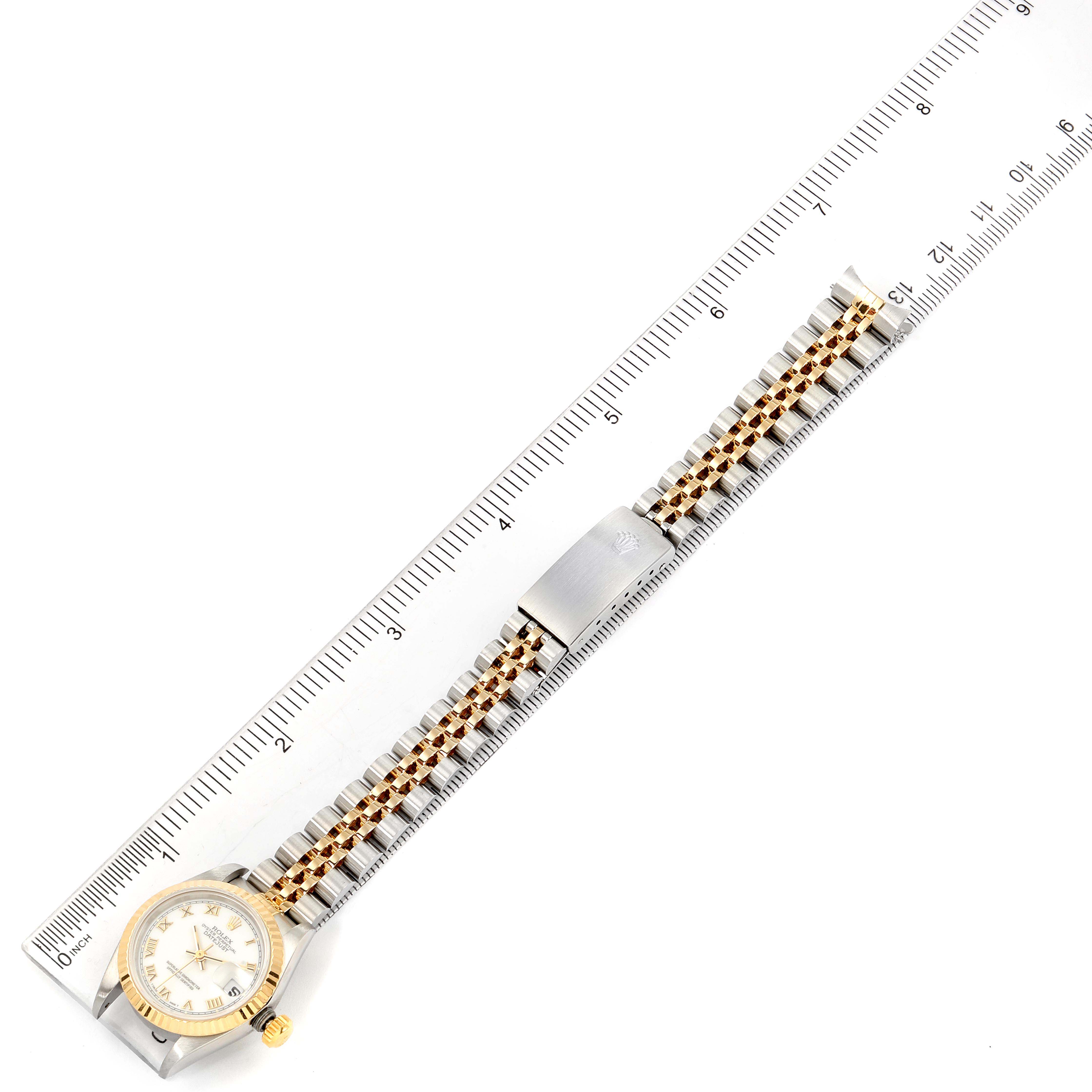 The image shows a Rolex Datejust 69173 Women's Steel and Gold (two tone) White Dial 69173 Women's Steel and Gold (two tone) White Dial watch laid flat, highlighting its band, clasp, and face alongside a ruler for scale.