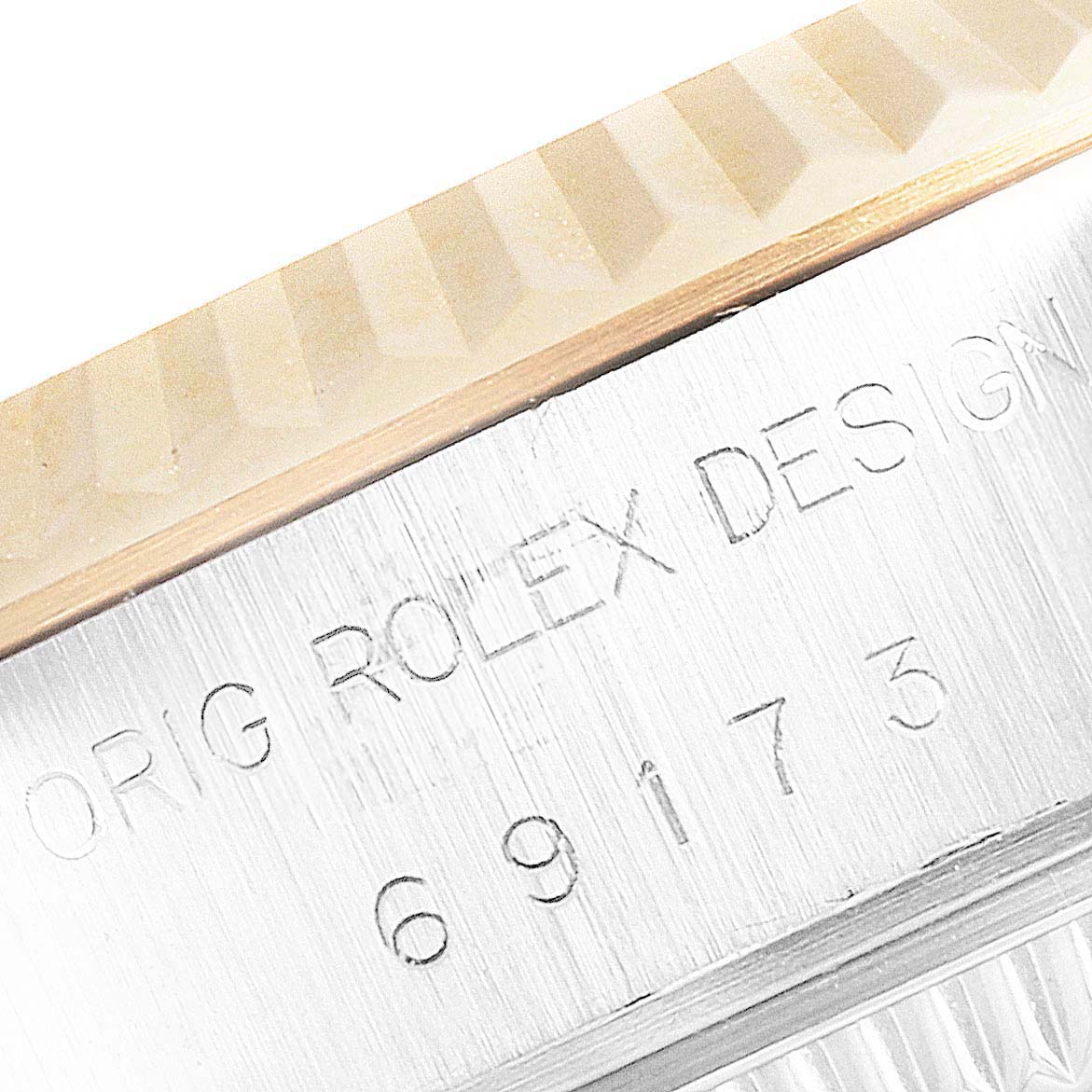 The image shows a close-up of the Rolex Datejust 69173 Women's Steel and Gold (two tone) White Dial 69173 Women's Steel and Gold (two tone) White Dial with a focus on the engraved case and part of the fluted bezel.