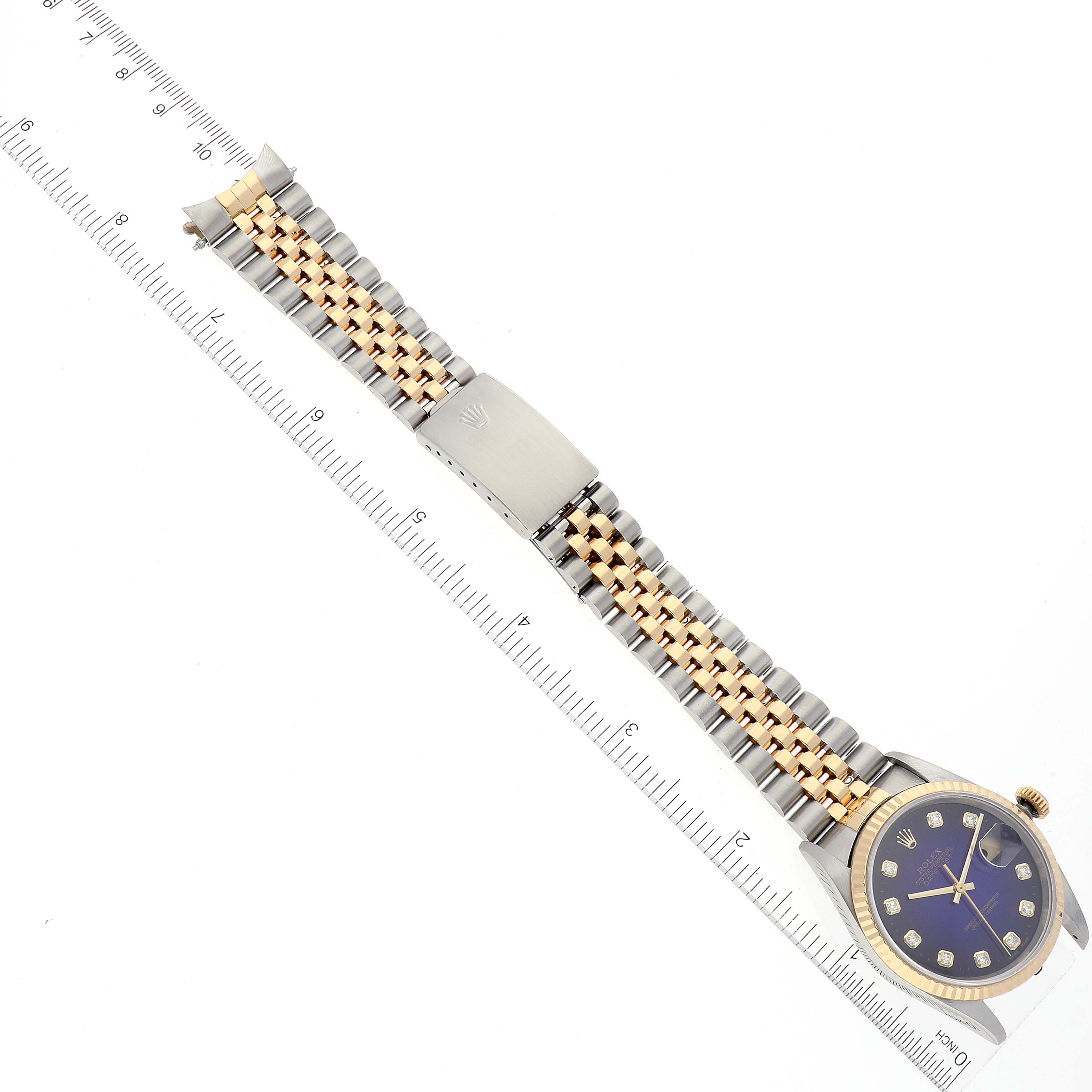 This image shows a Rolex Datejust 16233 Men's Steel and Gold (two tone) Purple Dial 16233 Men's Steel and Gold (two tone) Purple Dial watch laid flat, displaying its face, two-tone bracelet, and clasp alongside a ruler for scale.