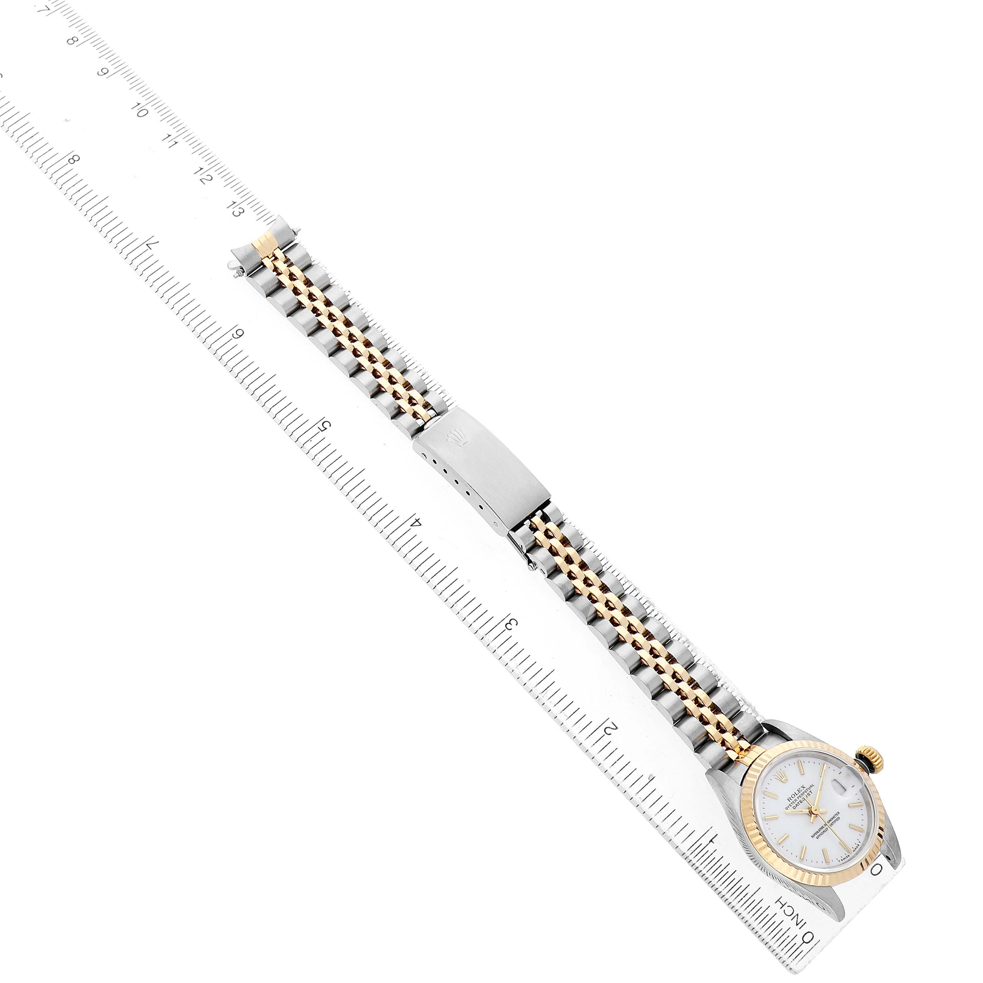 The Rolex Datejust 69173 Women's Steel and Gold (two tone) White Dial watch is shown diagonally from the side, highlighting the bracelet and clasp alongside a measuring ruler.