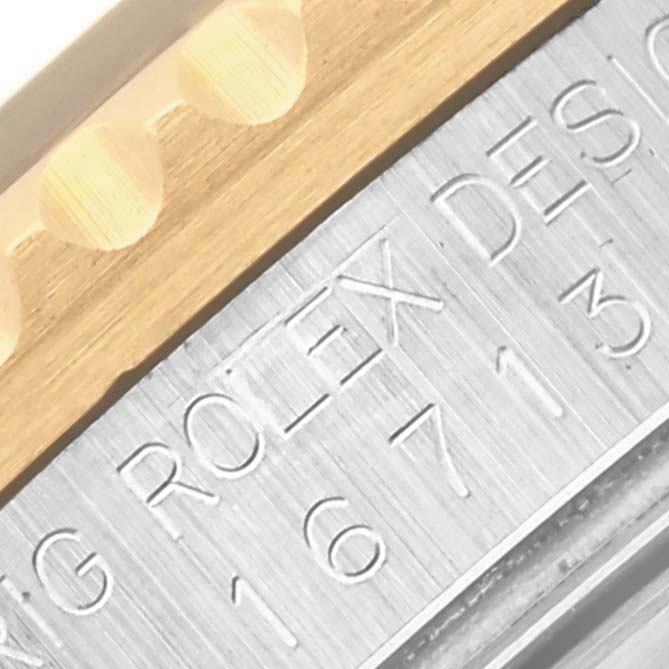 The image shows a close-up of the Rolex GMT-Master 16713 Men's Steel and Gold (two tone) Black Dial 16713 Men's Steel and Gold (two tone) Black Dial's engraved inner bezel and part of the serrated edge of the outer bezel.