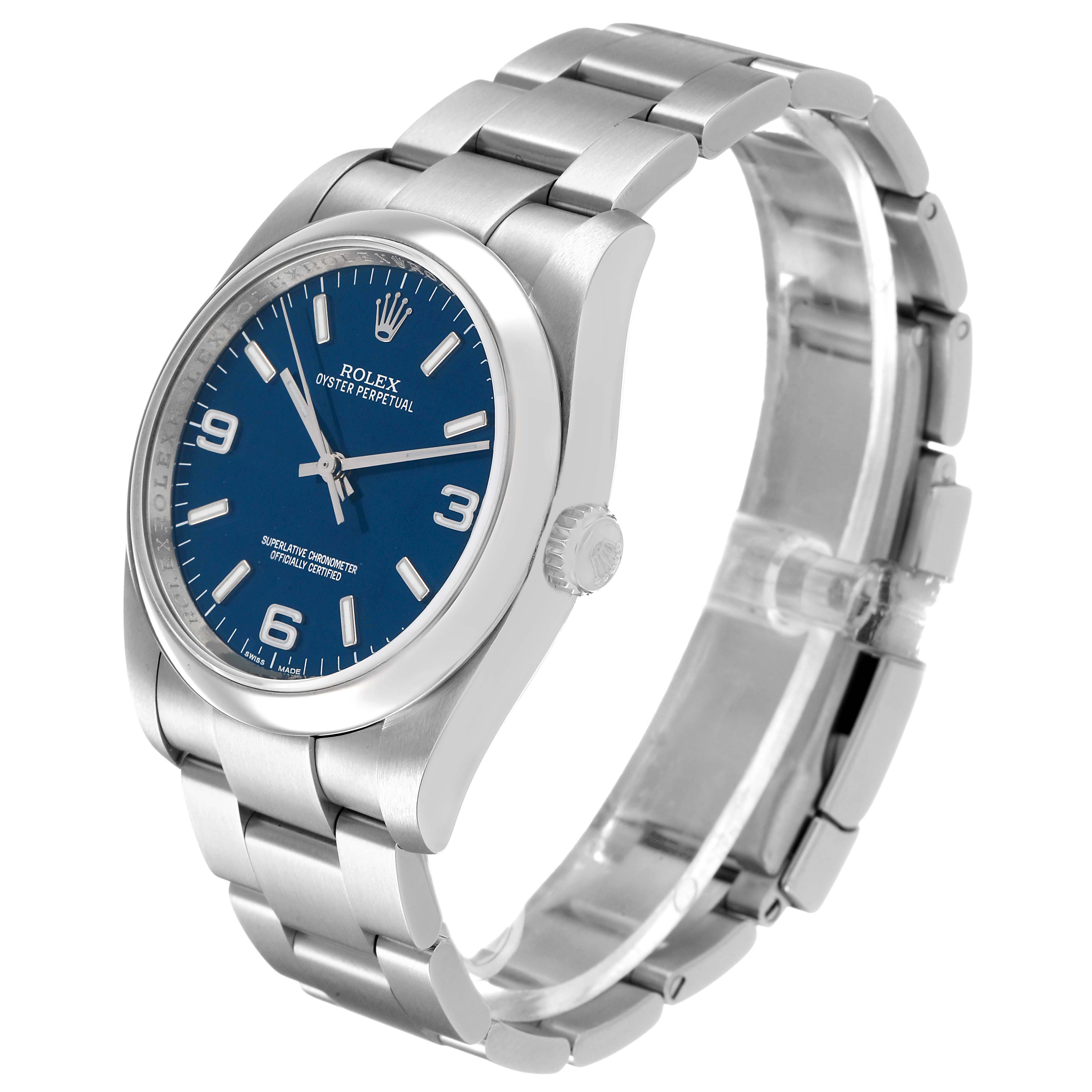 The Rolex Oyster Perpetual 116000 Men's Stainless Steel Blue Dial watch is shown at an angle displaying the watch face, bracelet, and crown.