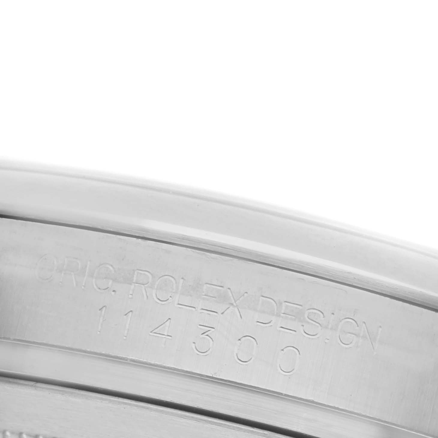 The image shows a close-up of the side of the Rolex Oyster Perpetual 114300 Men's Stainless Steel Grey Dial 114300 Men's Stainless Steel Grey Dial, highlighting the engraved serial number and brand design.