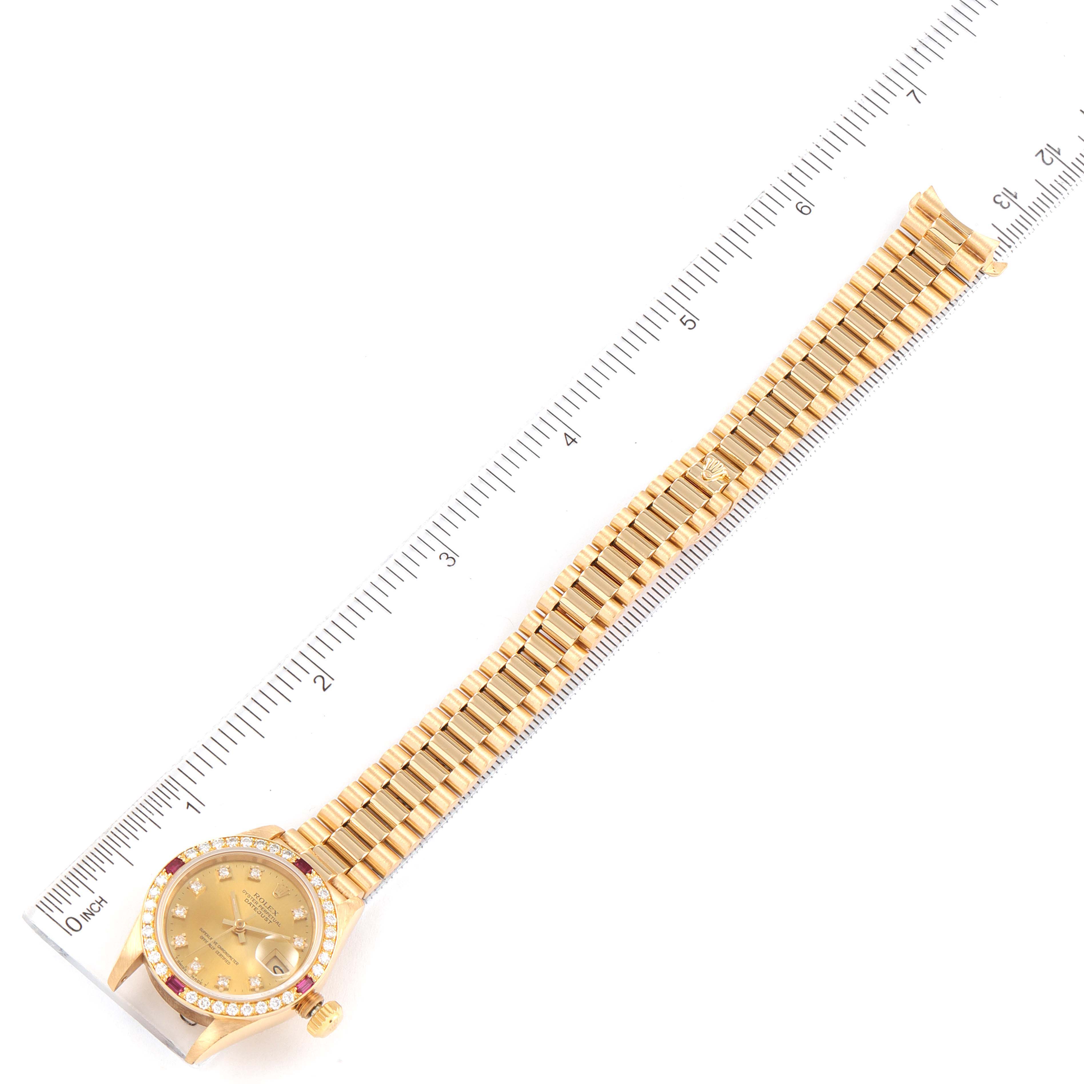 The image shows a Rolex President 69068 Women
s Yellow Gold Champagne Dial 69068 Women
s Yellow Gold Champagne Dial model watch laid flat next to a ruler, displaying the full bracelet and case from an overhead angle.