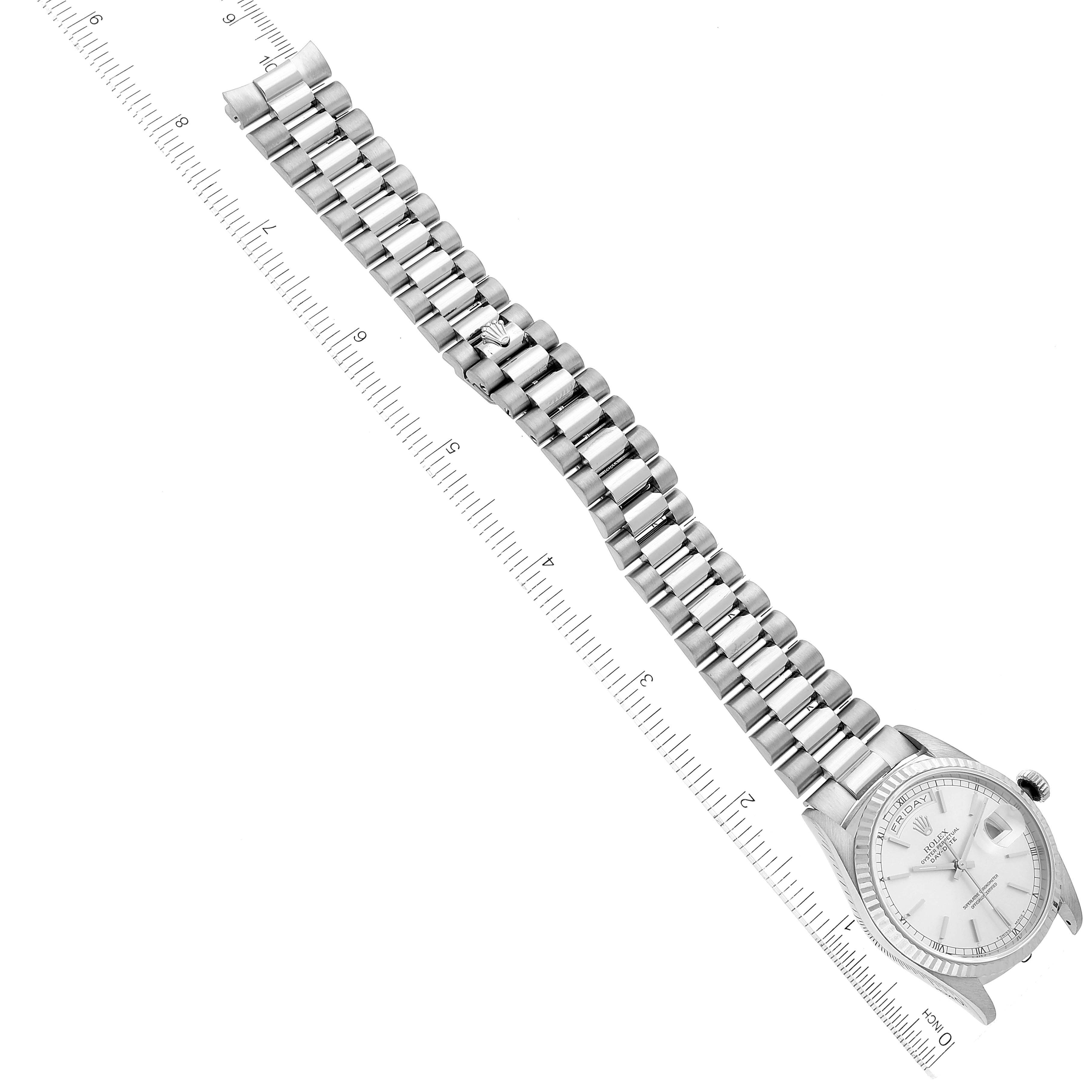 The image shows a President model Rolex watch flat on its back, displaying the watch face, band, and a measuring ruler.