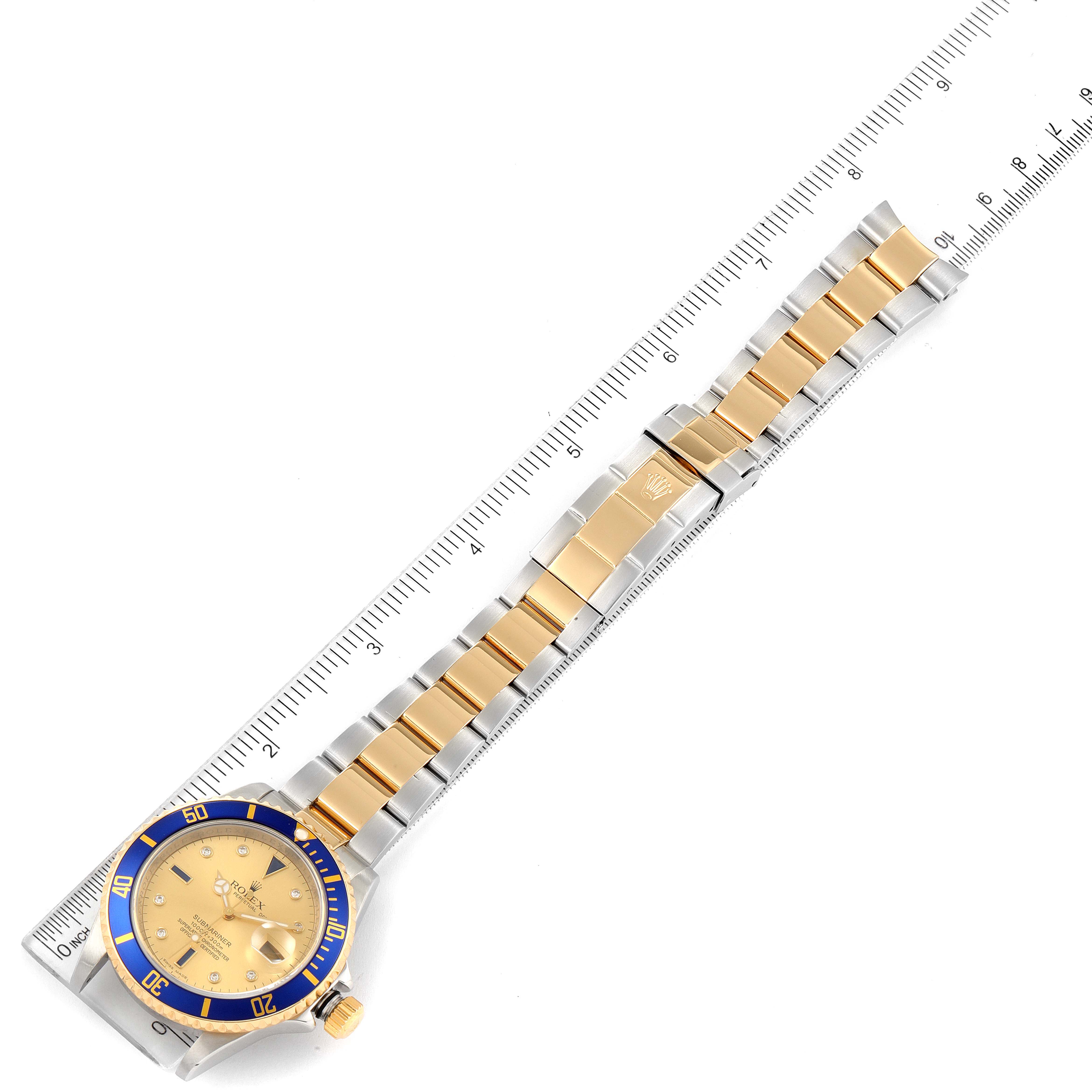 This image shows a top-down view of a Rolex Submariner 16613 Men's Steel and Gold (two tone) Champagne Dial 16613 Men's Steel and Gold (two tone) Champagne Dial watch, highlighting its band and face alongside a ruler for scale.