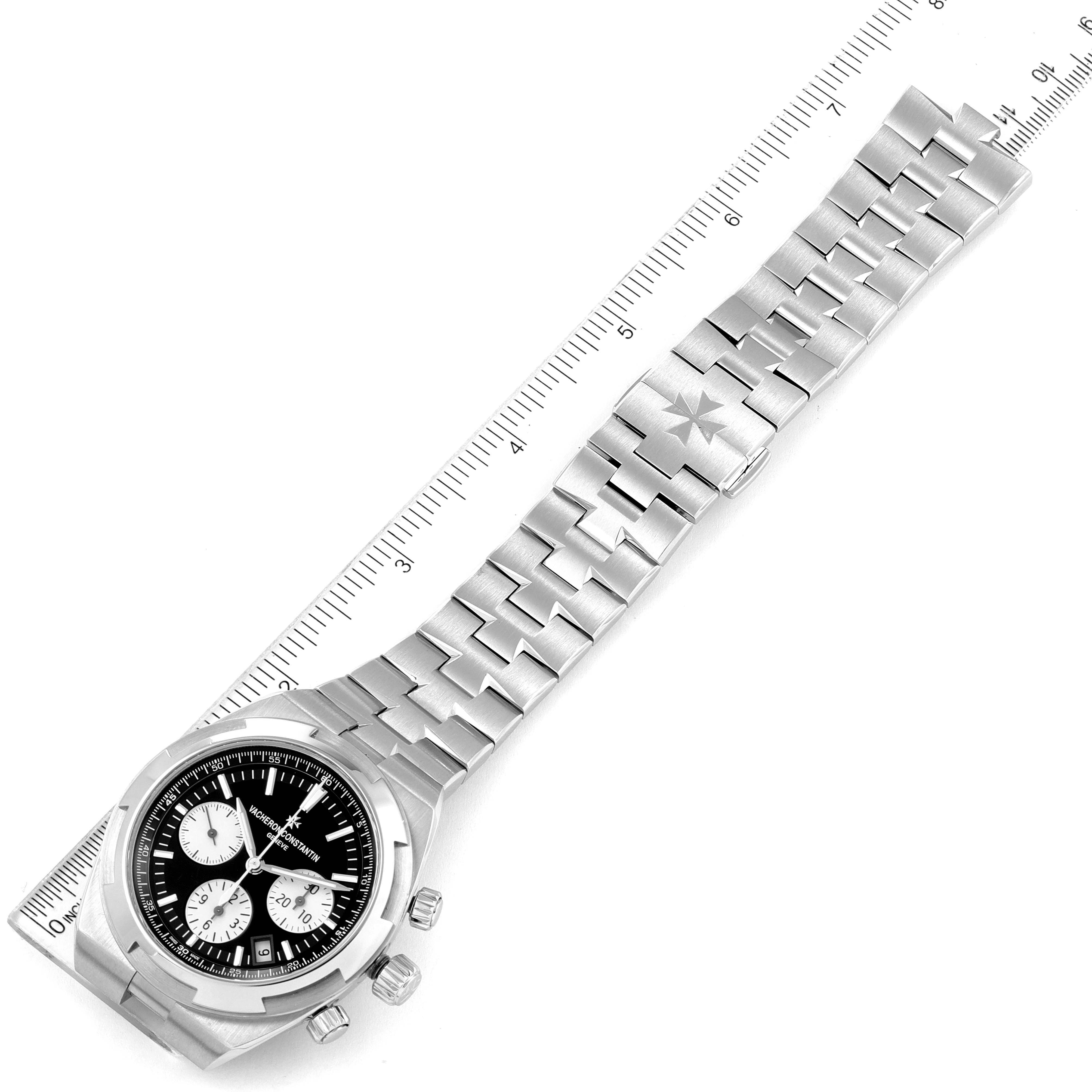 The Vacheron Constantin Overseas 5500V/110A-B481 Men's Stainless Steel Black Dial 5500V/110A-B481 Men's Stainless Steel Black Dial watch is shown from a top angle, displaying both the face and full metal bracelet beside a ruler.